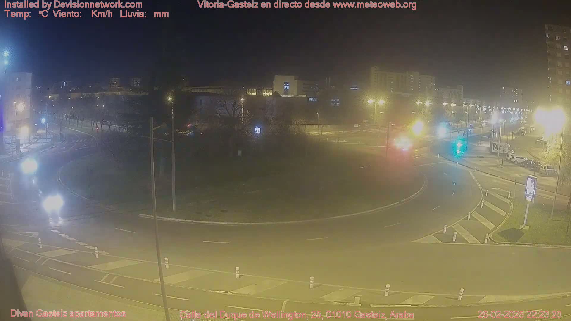 A nighttime view of a roundabout with cars and streetlights, under clear skies.