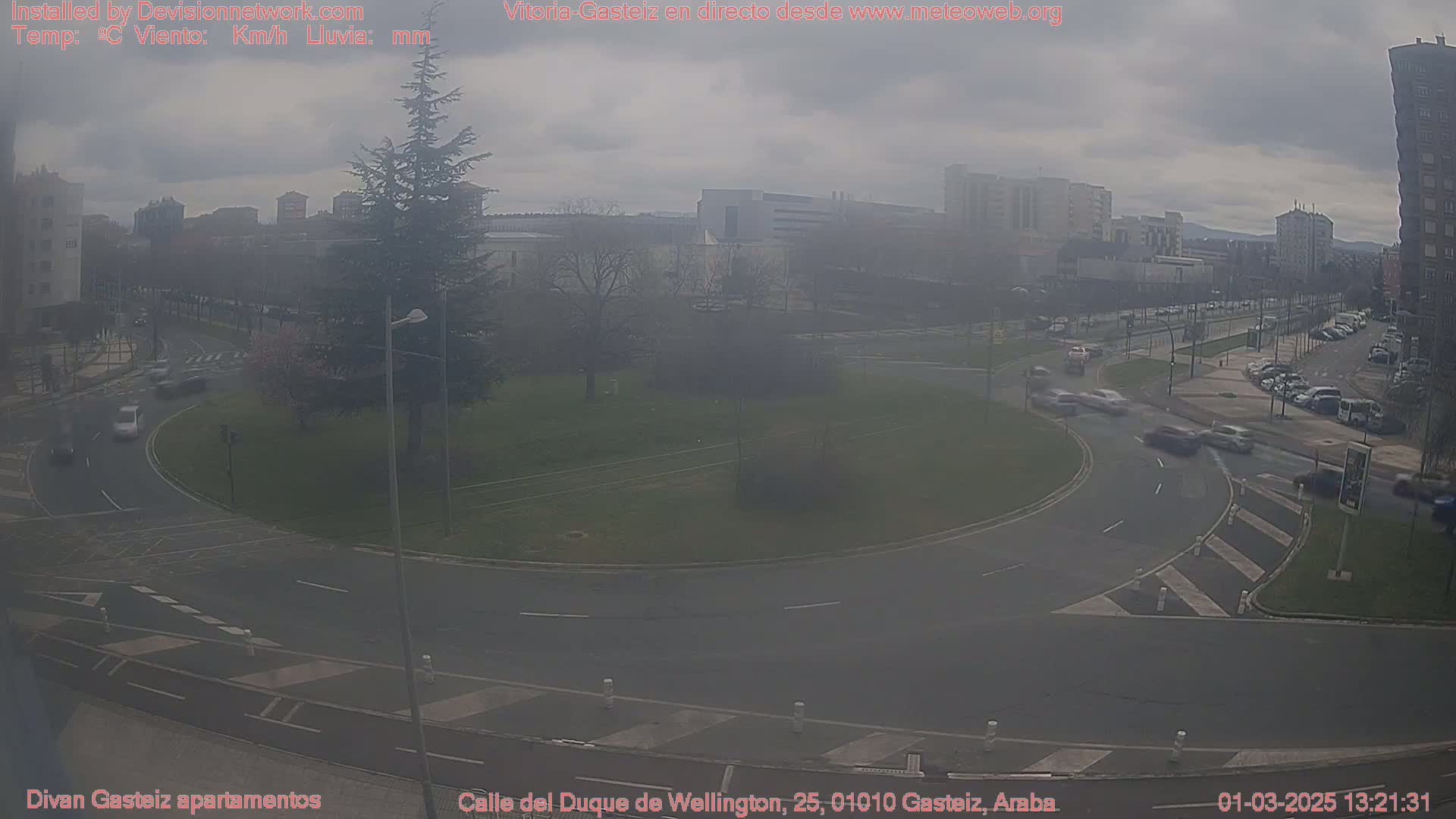 A hazy, overcast day reveals a roundabout surrounded by buildings and a few cars in motion.