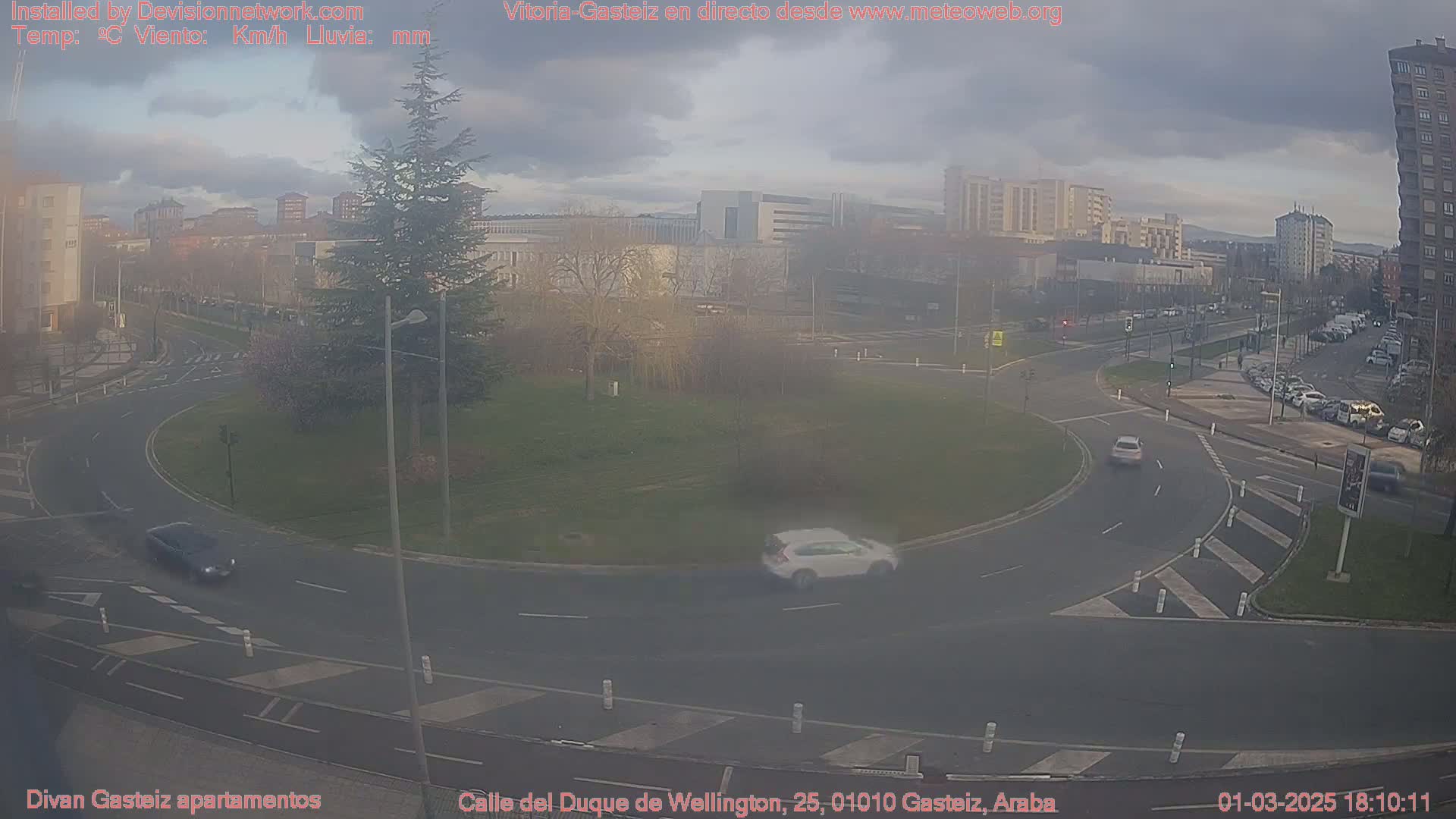 A hazy, overcast day reveals a roundabout surrounded by buildings and cars in a city.