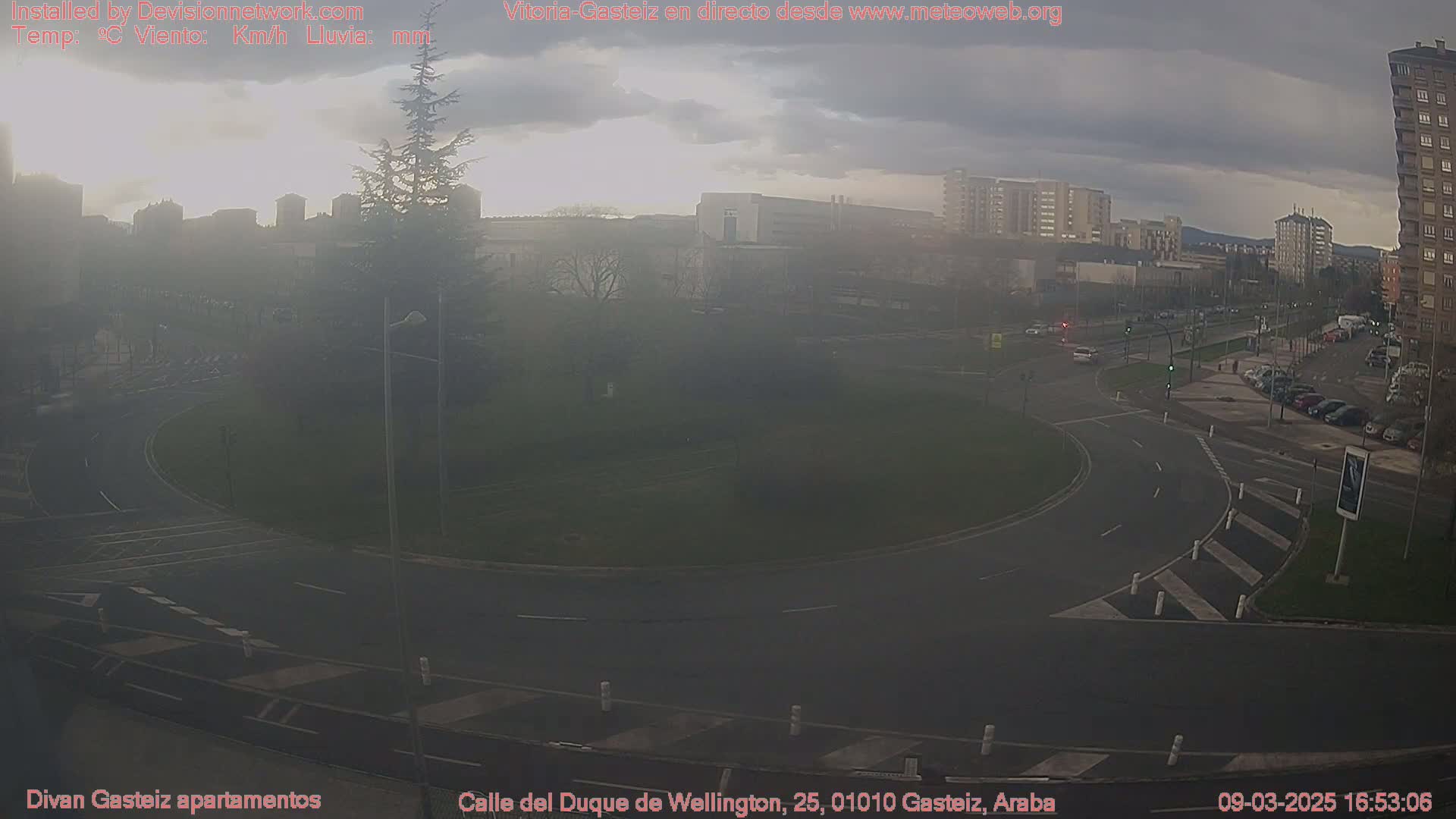 A hazy view of a roundabout and surrounding city streets under an overcast sky.