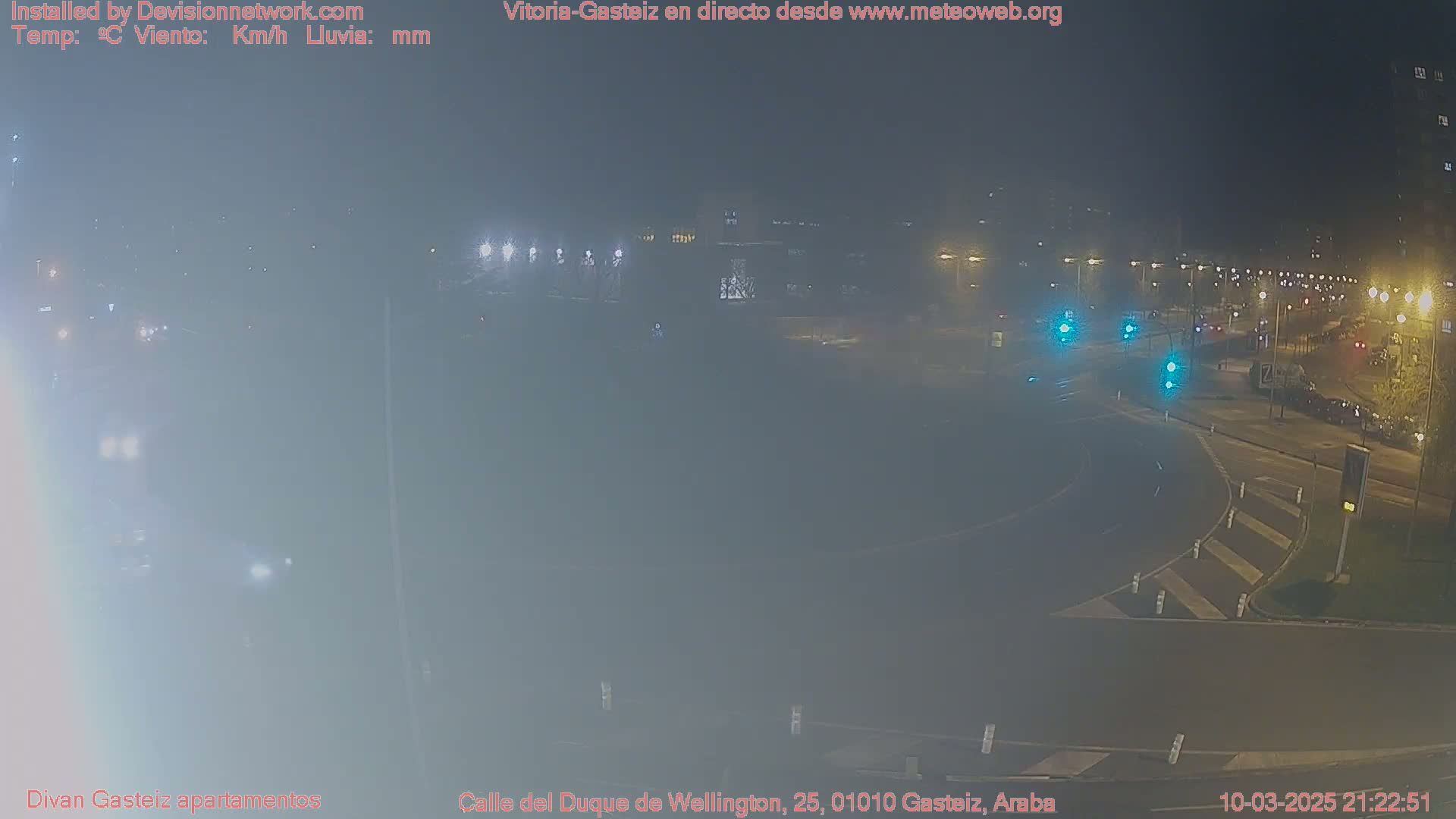 A hazy night scene shows a roundabout with cars and streetlights illuminated in a city.