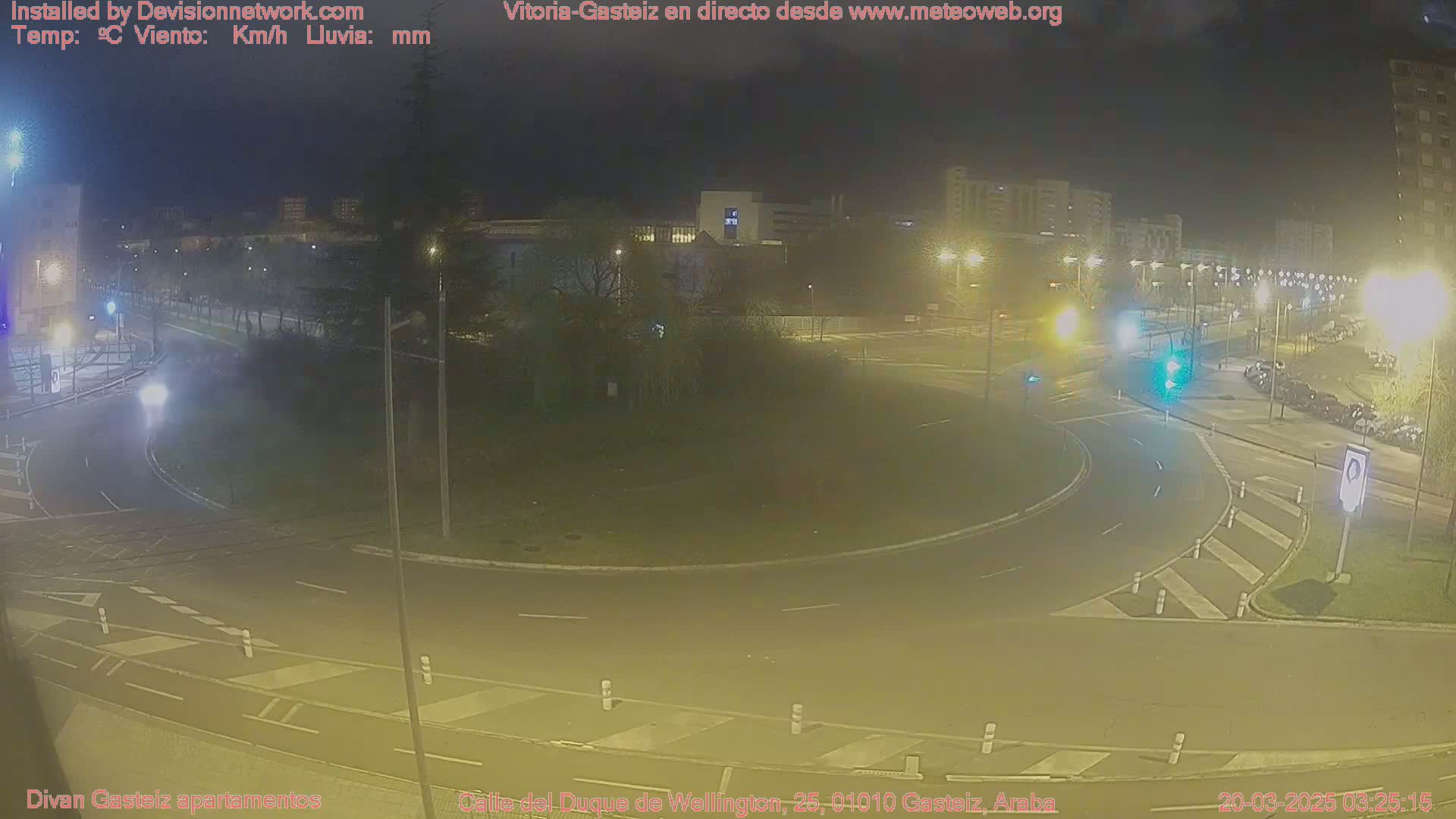 A nighttime view of a roundabout surrounded by buildings and streetlights.