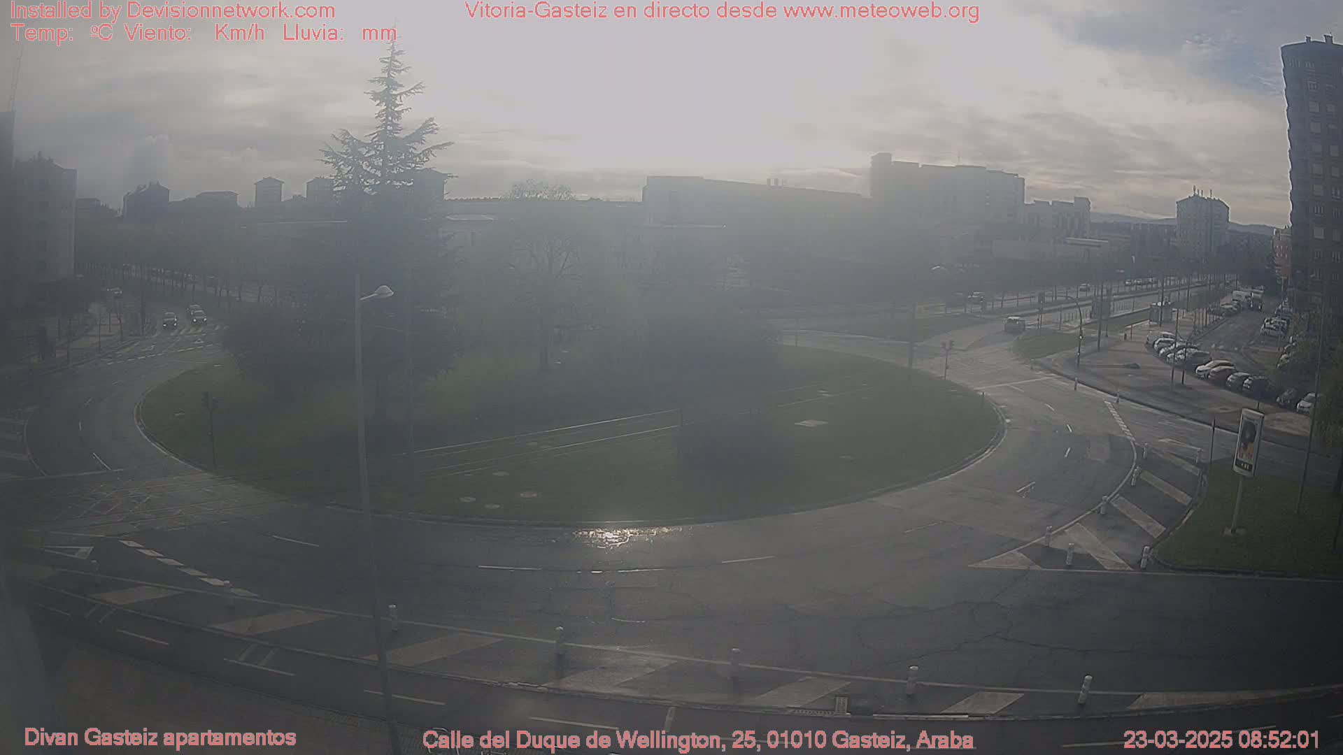 A hazy, overcast day reveals a roundabout surrounded by roads and buildings in a city.