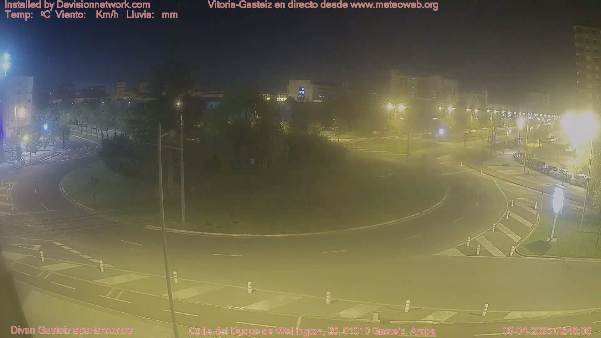 A nighttime view of a roundabout and surrounding streets, illuminated by streetlights.