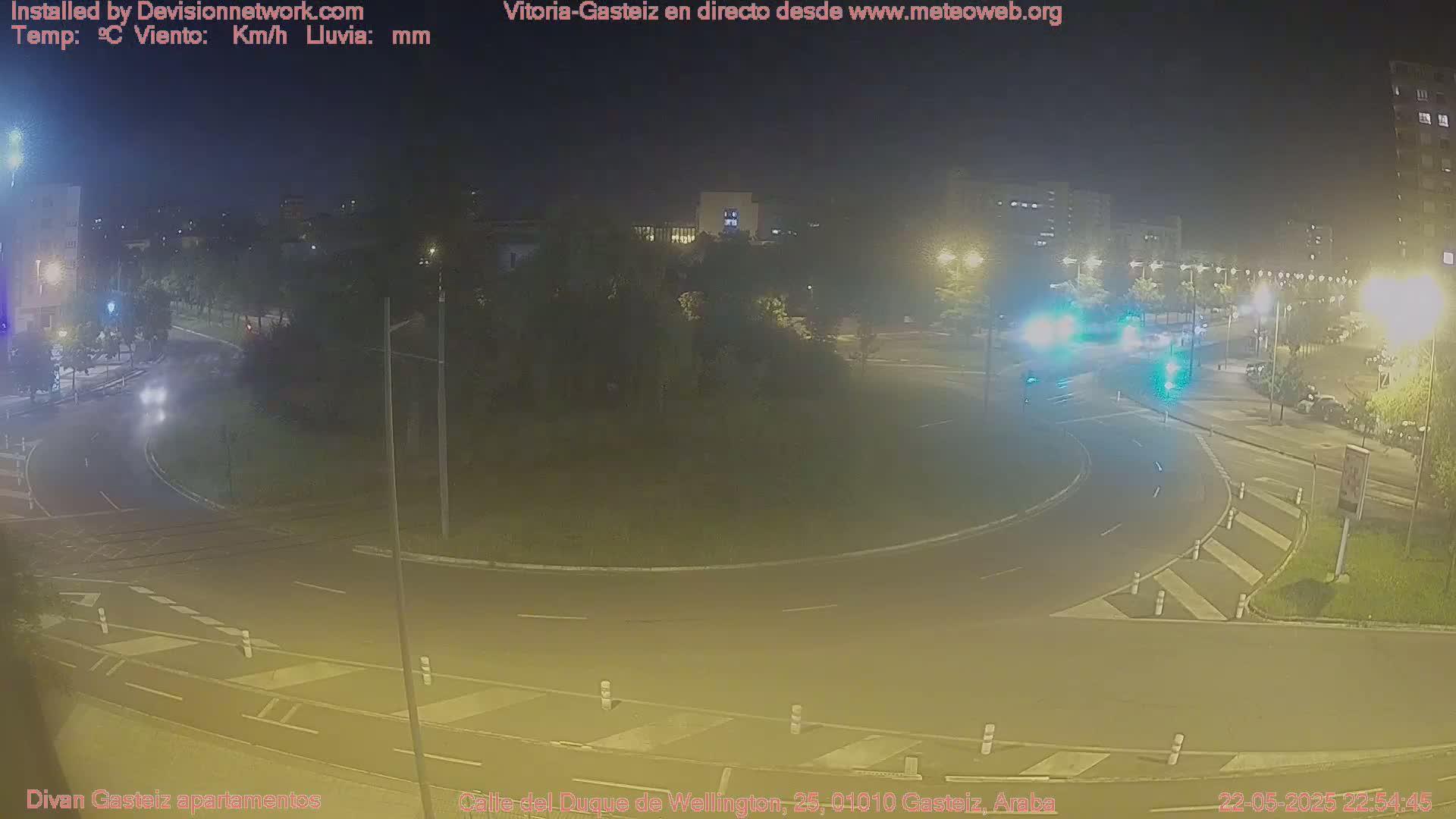 A nighttime, low-light view of a traffic roundabout with minimal vehicle traffic.