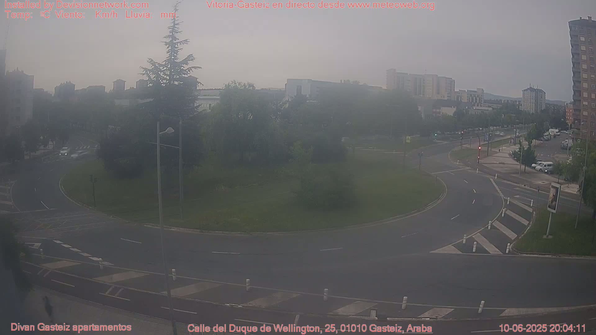A hazy view of a roundabout in a city, with some cars visible and buildings in the background.
