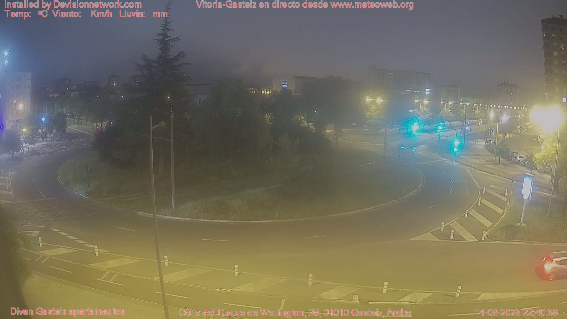 A hazy overcast day reveals a roundabout in a city with surrounding buildings and green spaces.