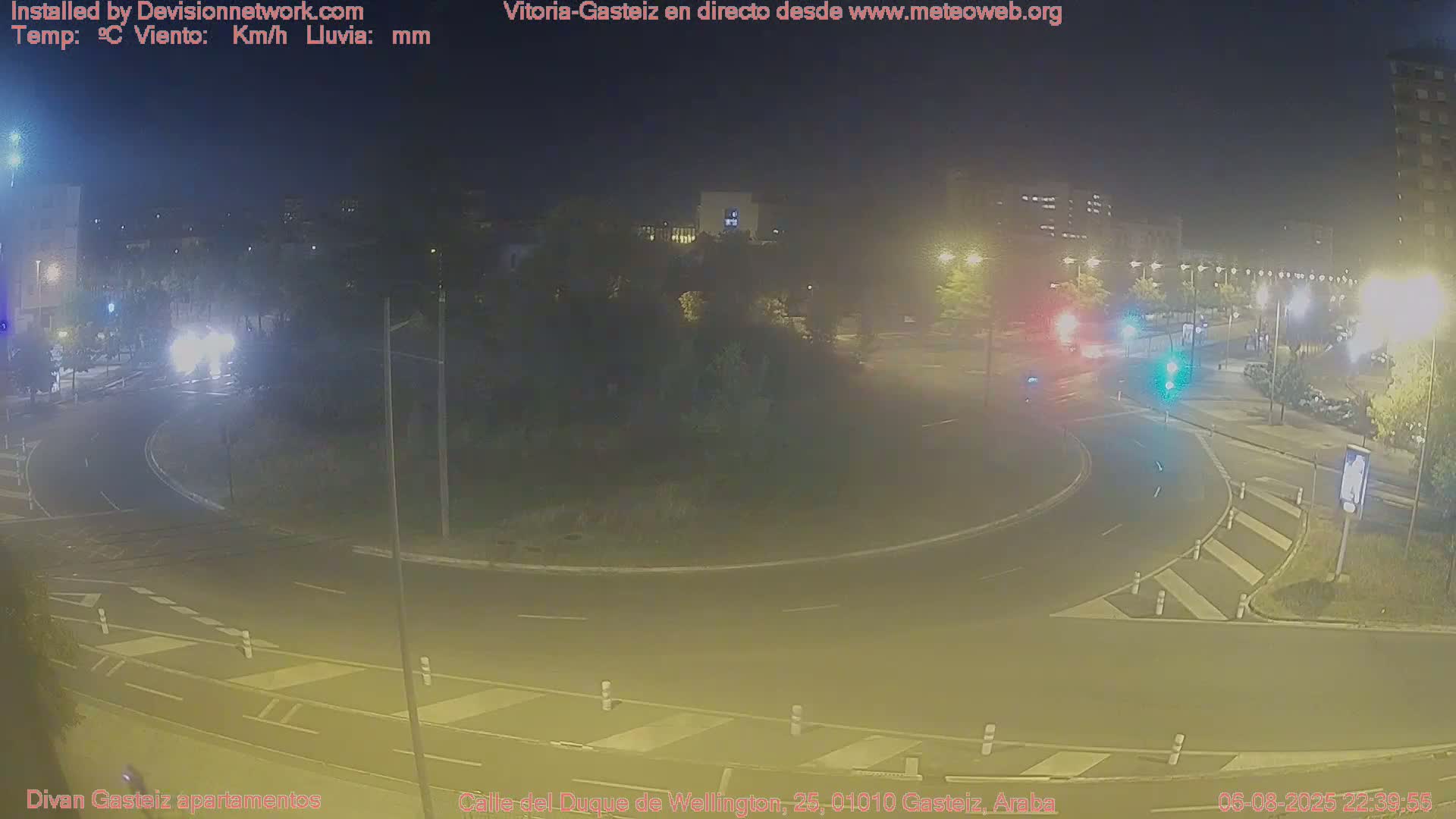 A nighttime view of a roundabout with minimal traffic under hazy, dimly lit conditions.