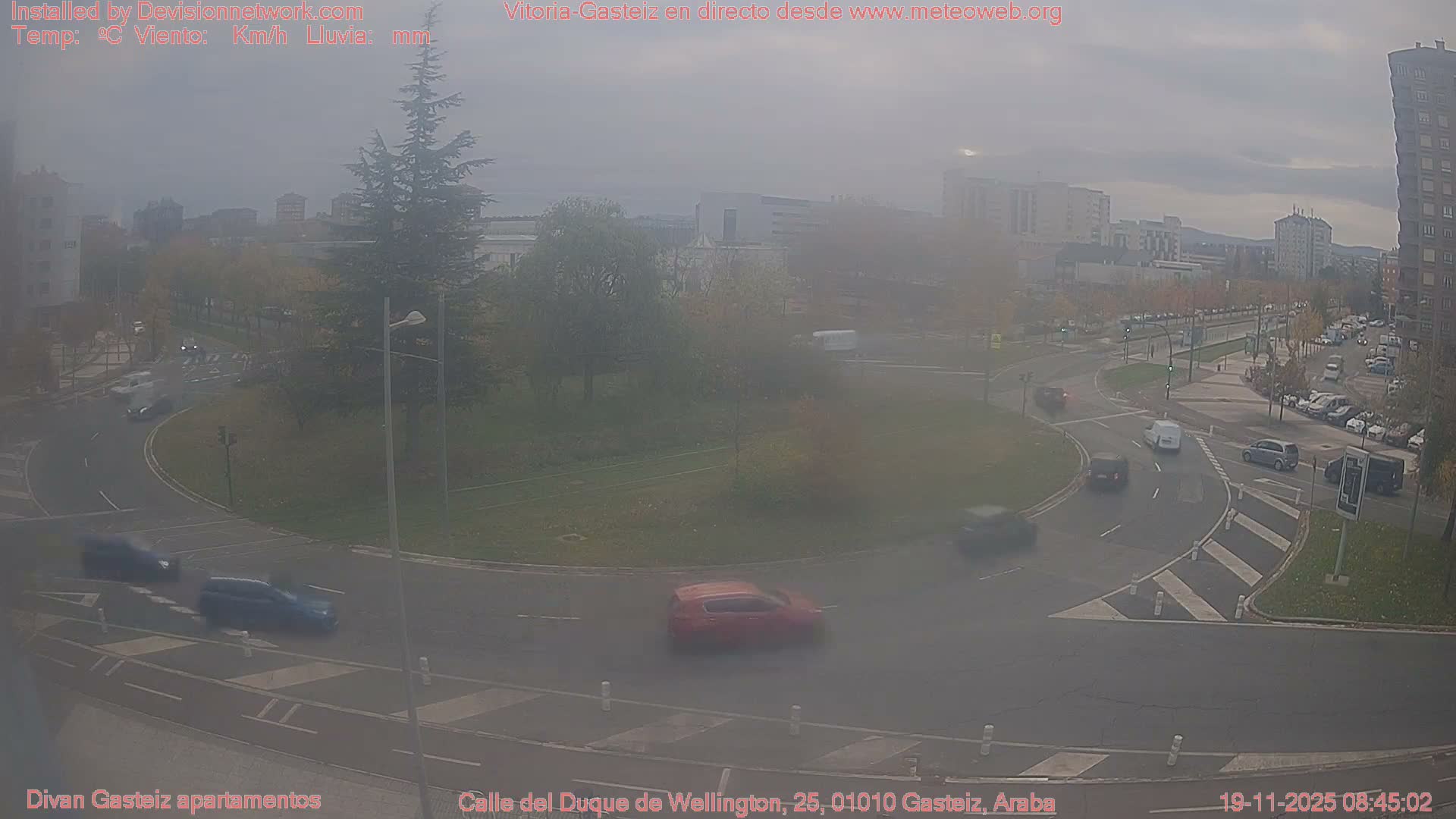 A nighttime view of a roundabout with minimal traffic under hazy, dimly lit conditions.