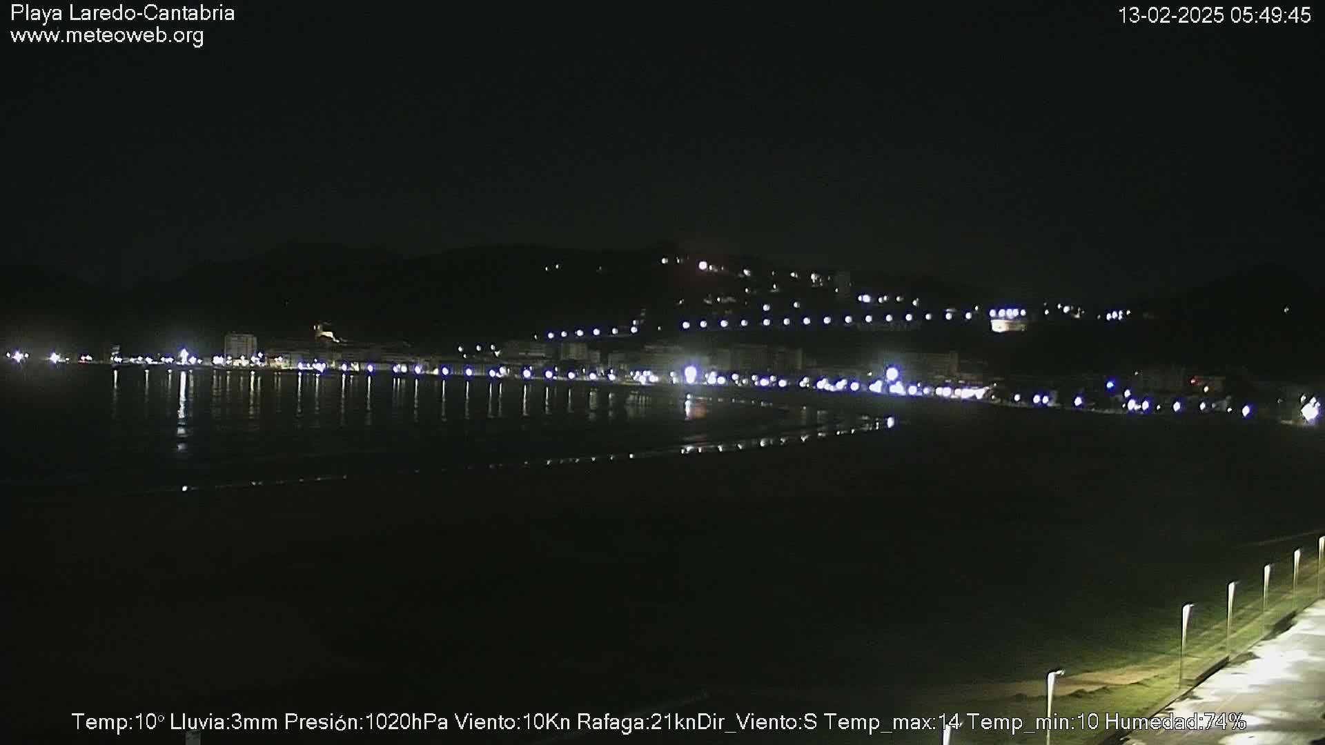 A nighttime view of a dimly lit beach town on a dark, slightly rainy night.
