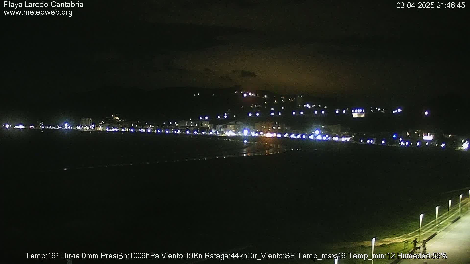 A nighttime view of a dimly lit beach town with a dark, overcast sky.