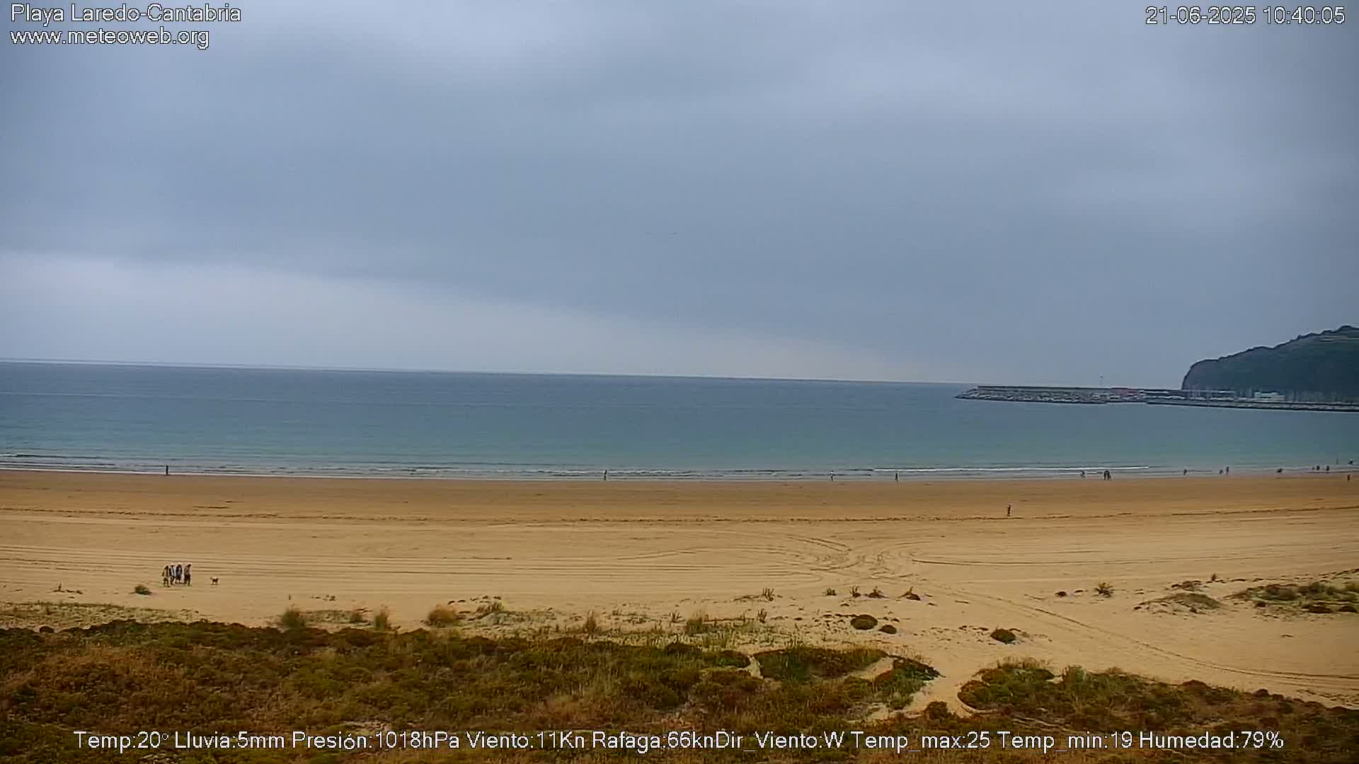 A long sandy beach stretches to a calm, gray ocean under an overcast sky.