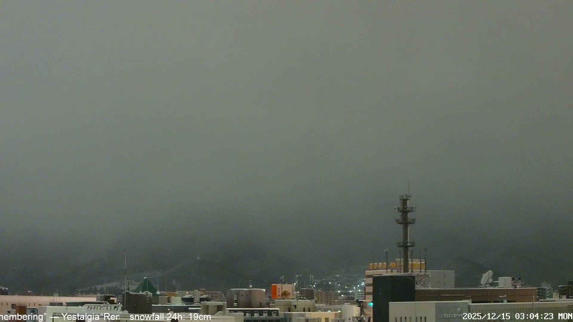 A clear, dark night sky hangs over a cityscape dotted with numerous illuminated buildings and streets, with a few bright, distant lights visible high above.