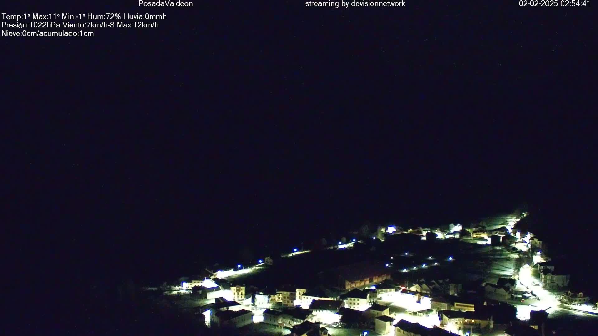 A small village at night is illuminated, under a clear, dark sky.