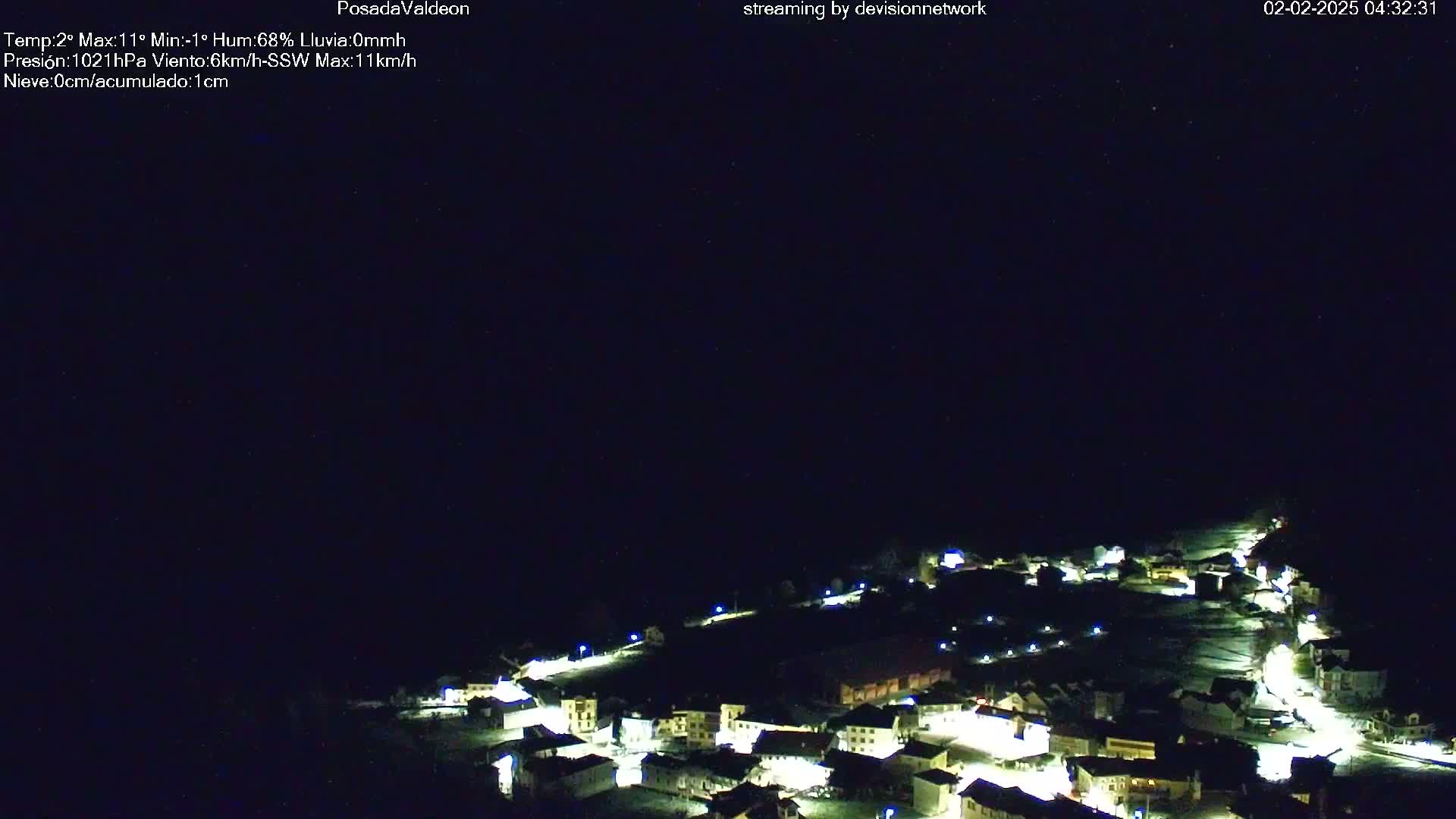 A small village at night is illuminated under a clear, dark sky.