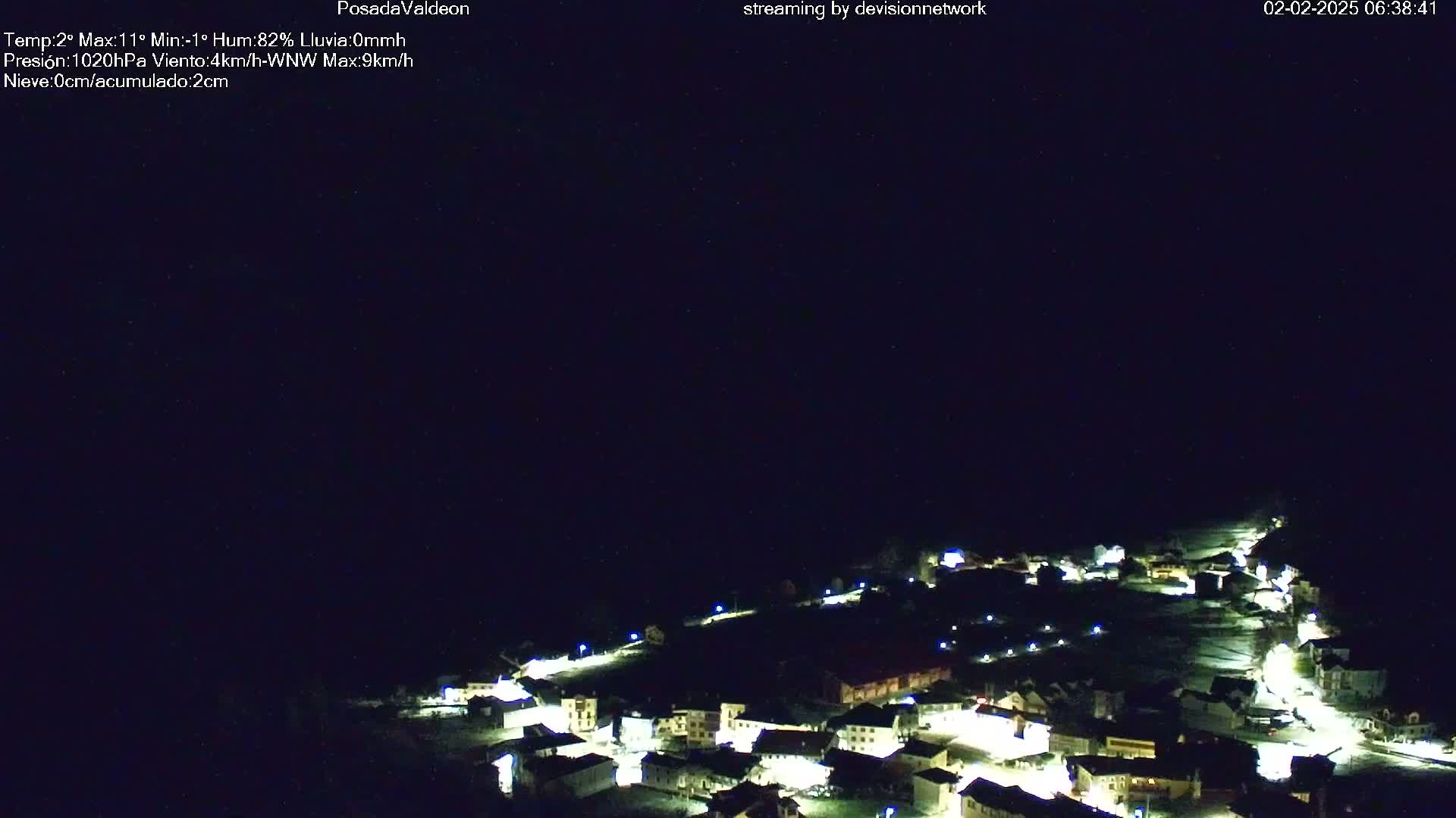 A small, snow-covered village is illuminated at night under a dark, clear sky.