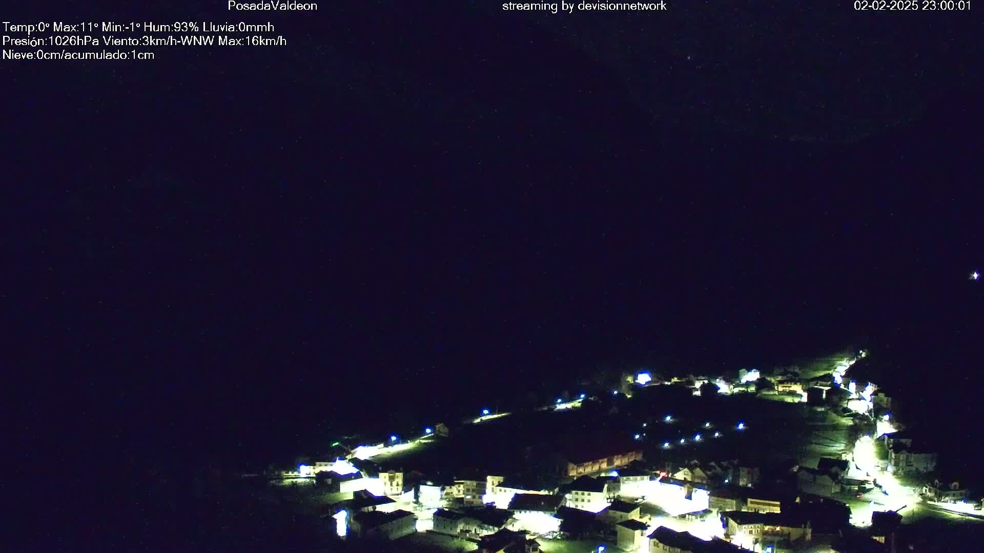 A nighttime view of a small village illuminated by lights under a dark, clear sky.