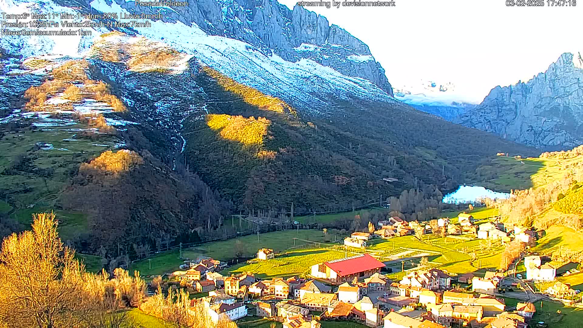 A small village nestled in a valley between snow-dusted mountains, bathed in the golden light of the setting sun.