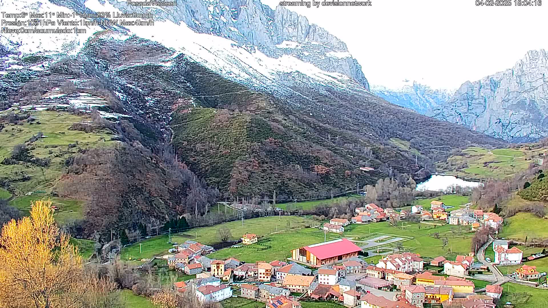 A small village nestled in a valley between snow-capped mountains on an overcast day.
