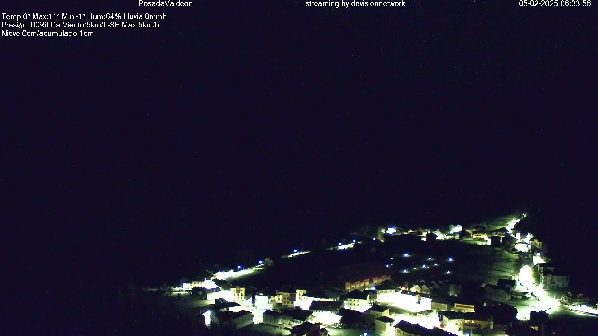 A small, snow-covered village is illuminated at night under a clear, dark sky.