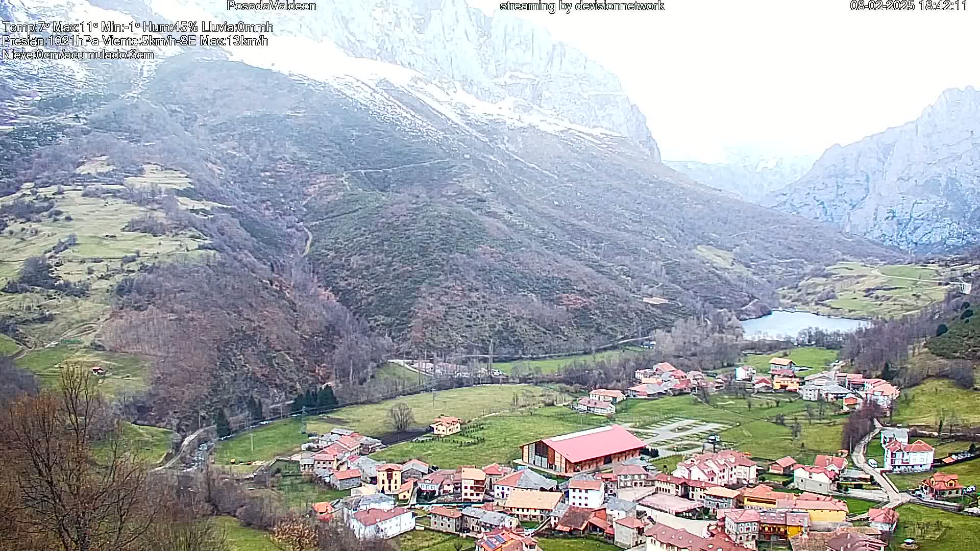 A small village nestled in a valley between snow-capped mountains on an overcast day.