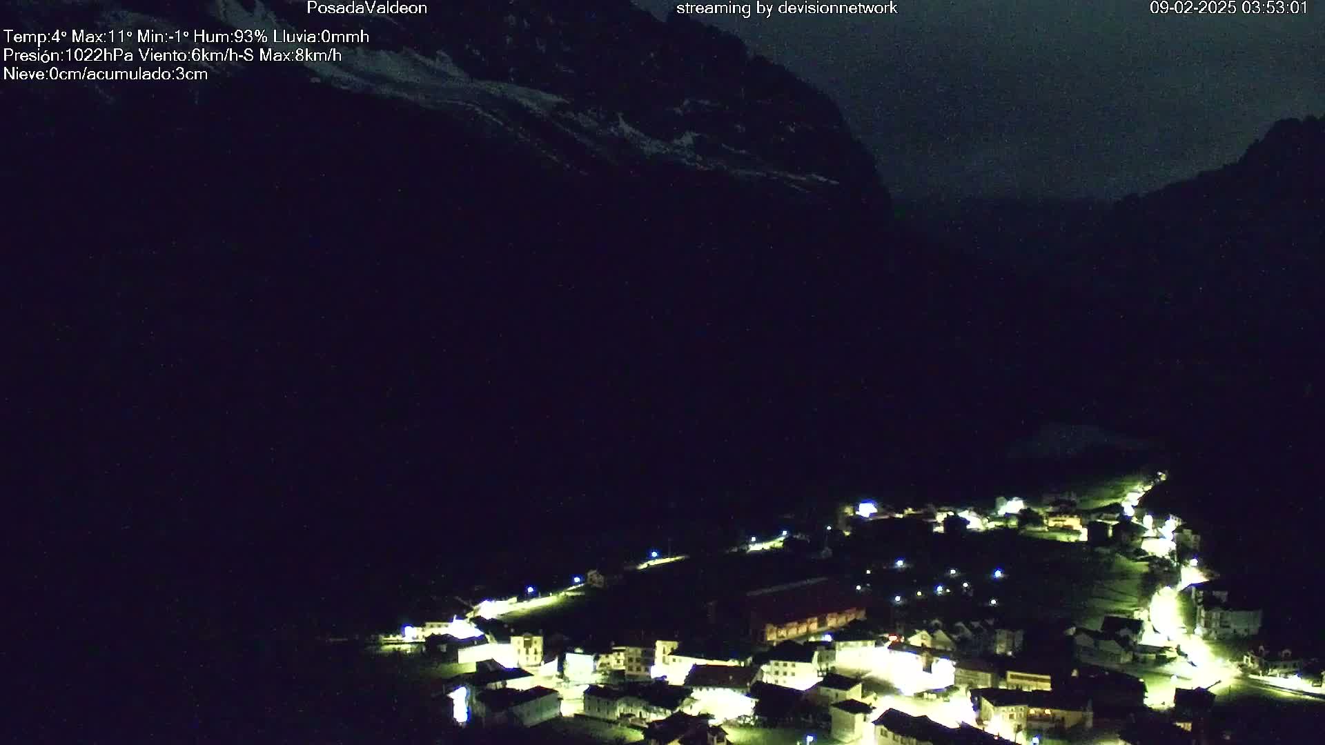 A small, illuminated village nestled in a dark valley under a night sky.