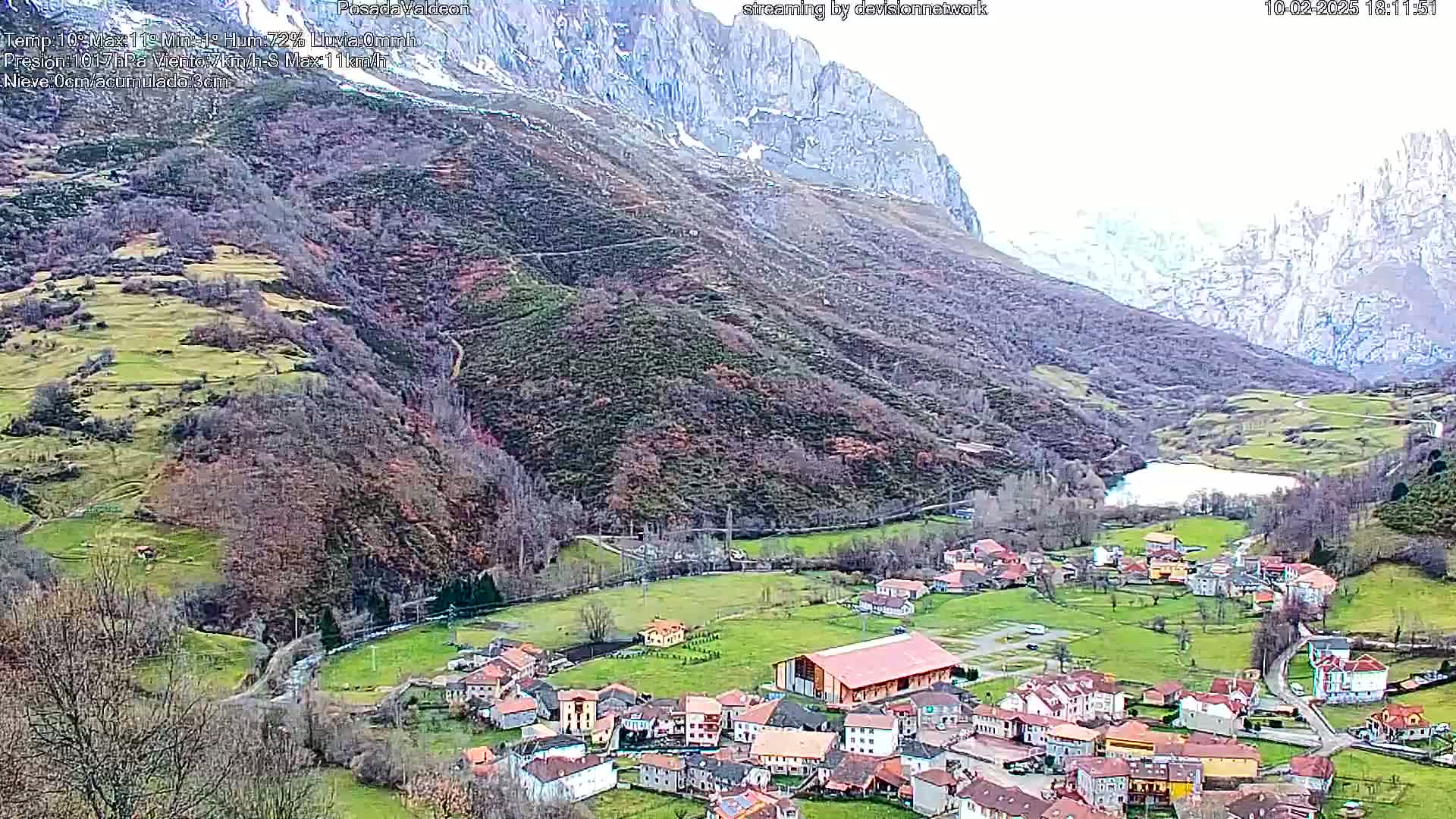 A small village nestled in a valley between snow-dusted mountains on an overcast day.
