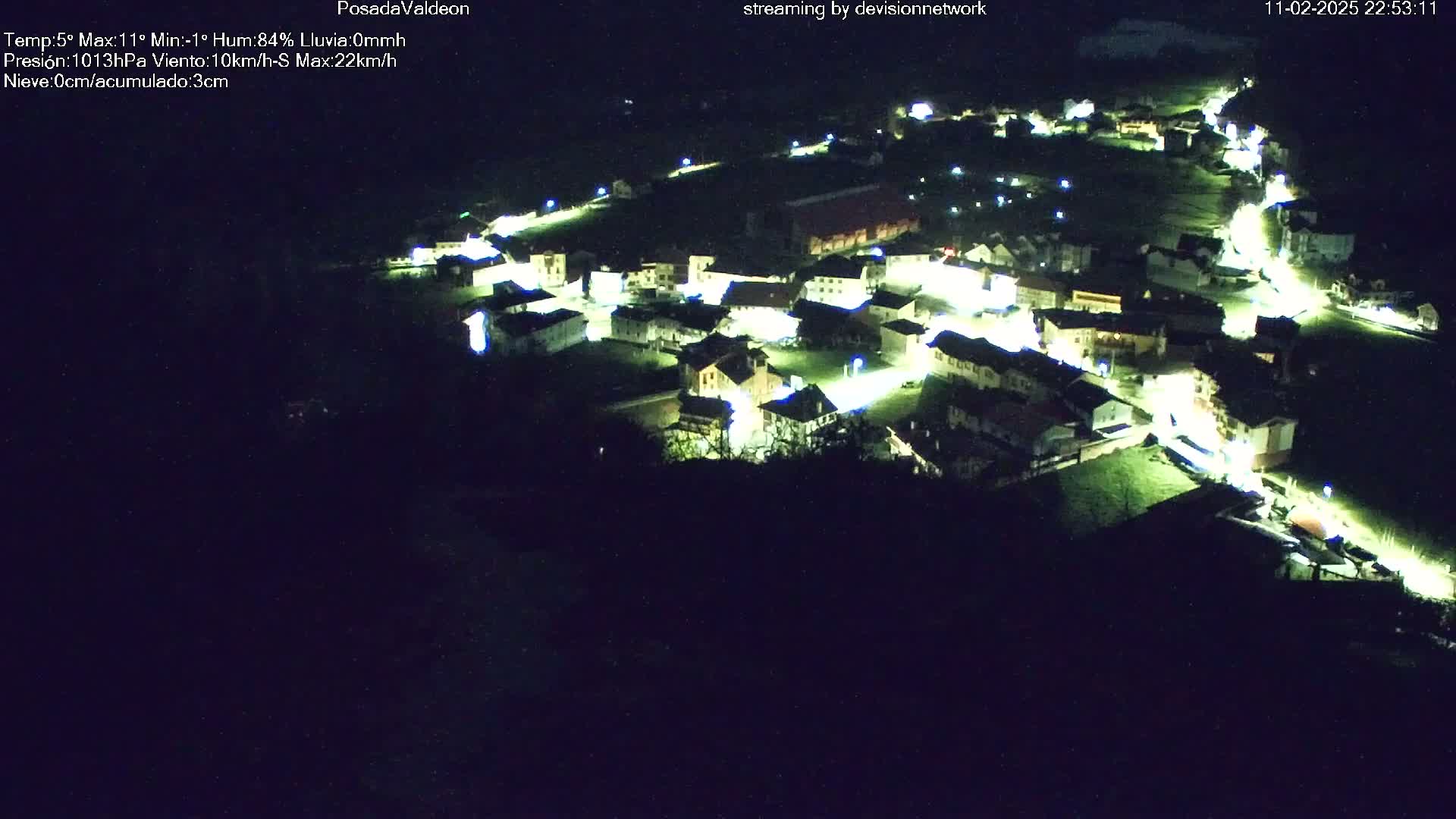 A nighttime aerial view of a small, illuminated town nestled in a dark landscape.