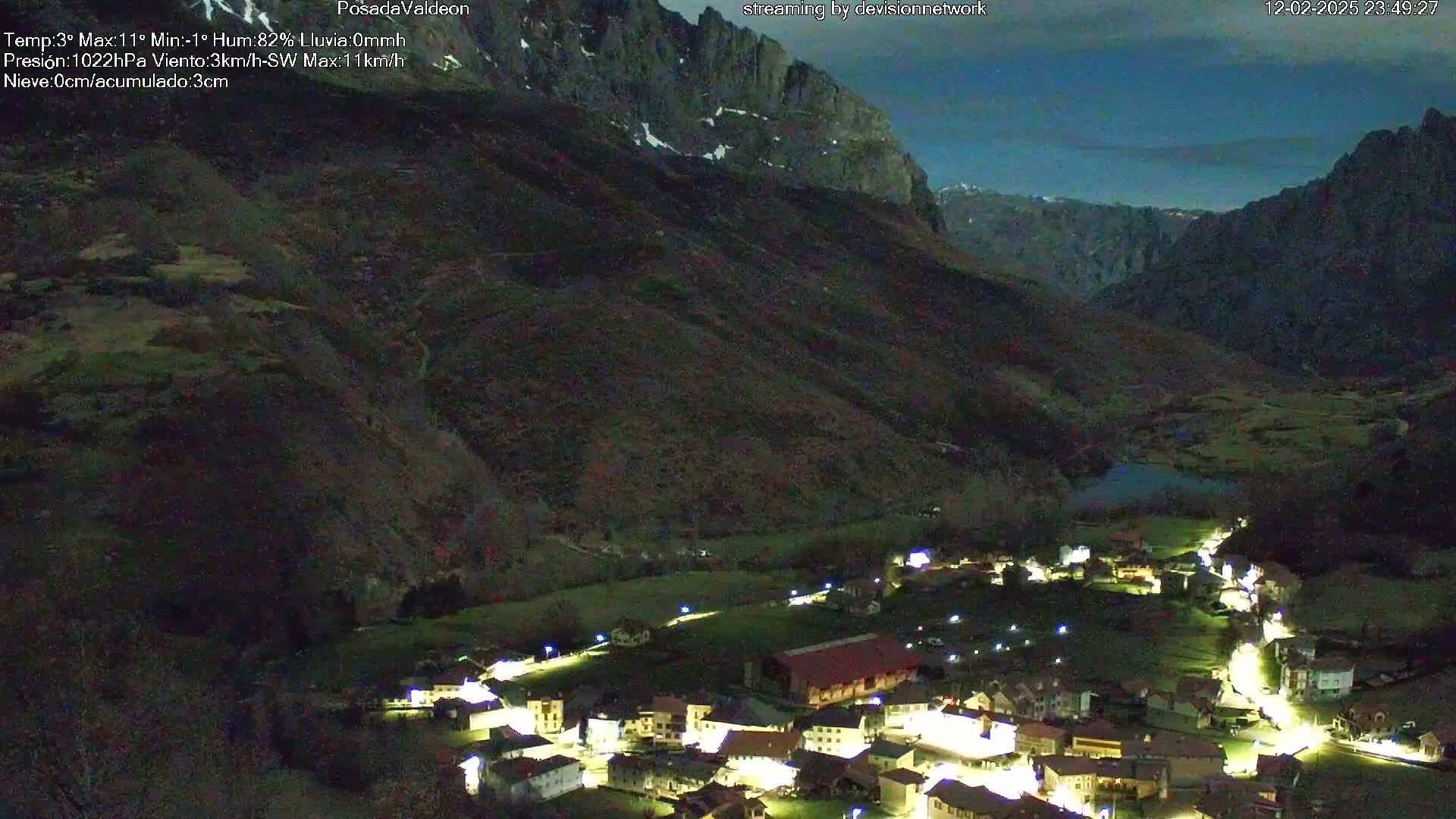 A small, illuminated village nestled in a valley between dark mountains under a twilight sky.