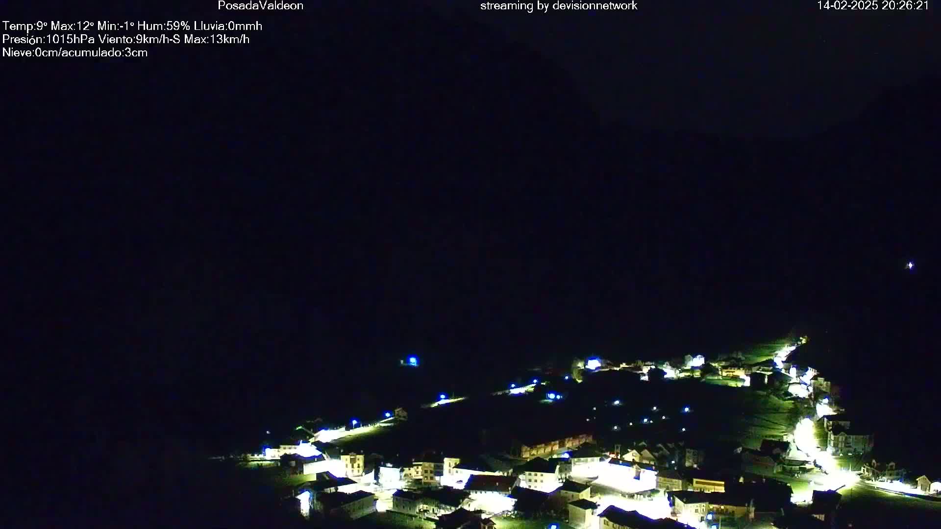 A small, illuminated village nestled in a dark valley at night under a clear, dark sky.