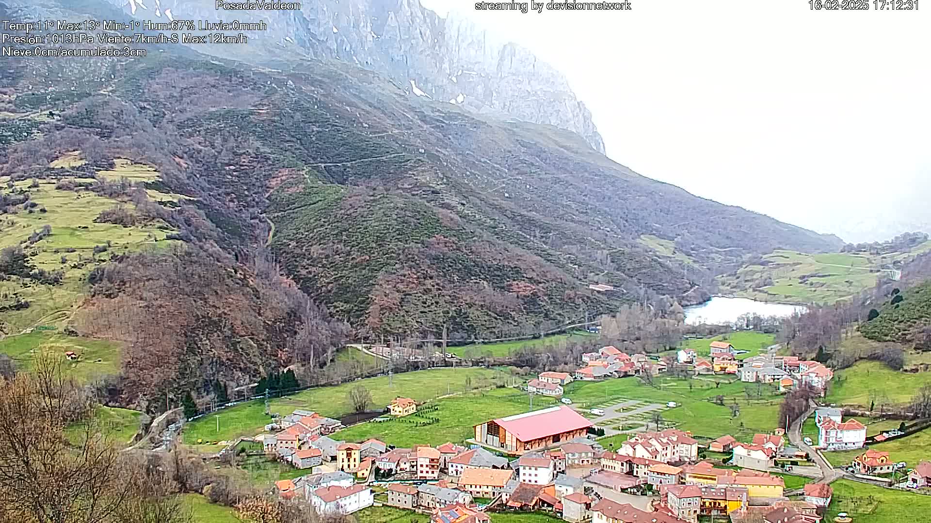 A small village nestled in a valley between mountains under an overcast sky.