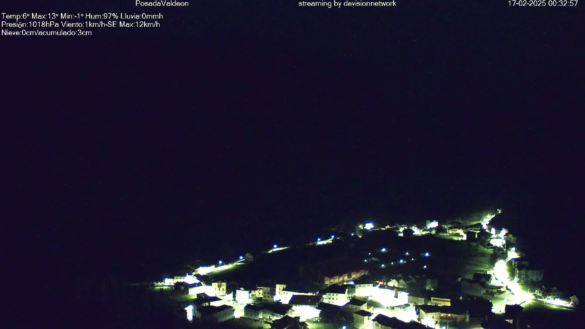 A nighttime, high-angle view of a small village illuminated by streetlights under a clear, dark sky.