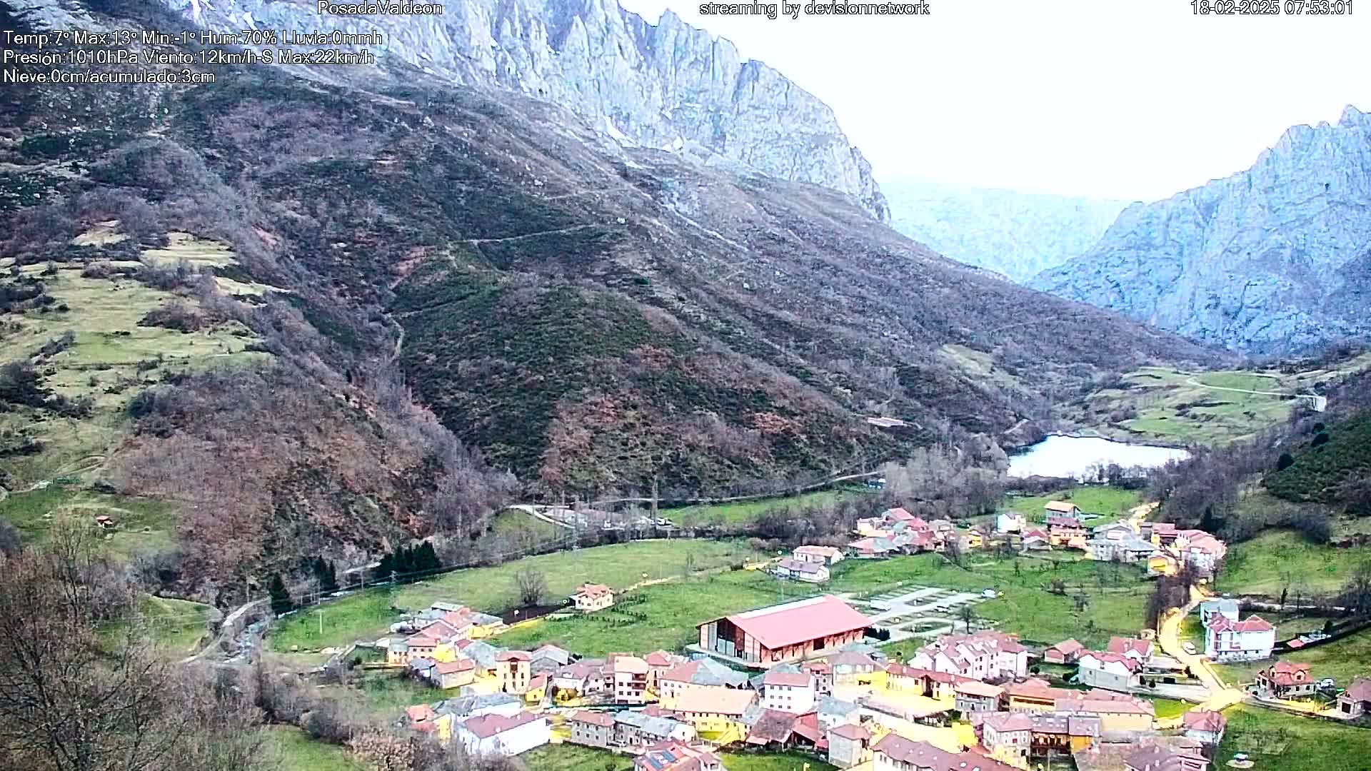 A small village nestled in a valley between mountains, under an overcast sky.