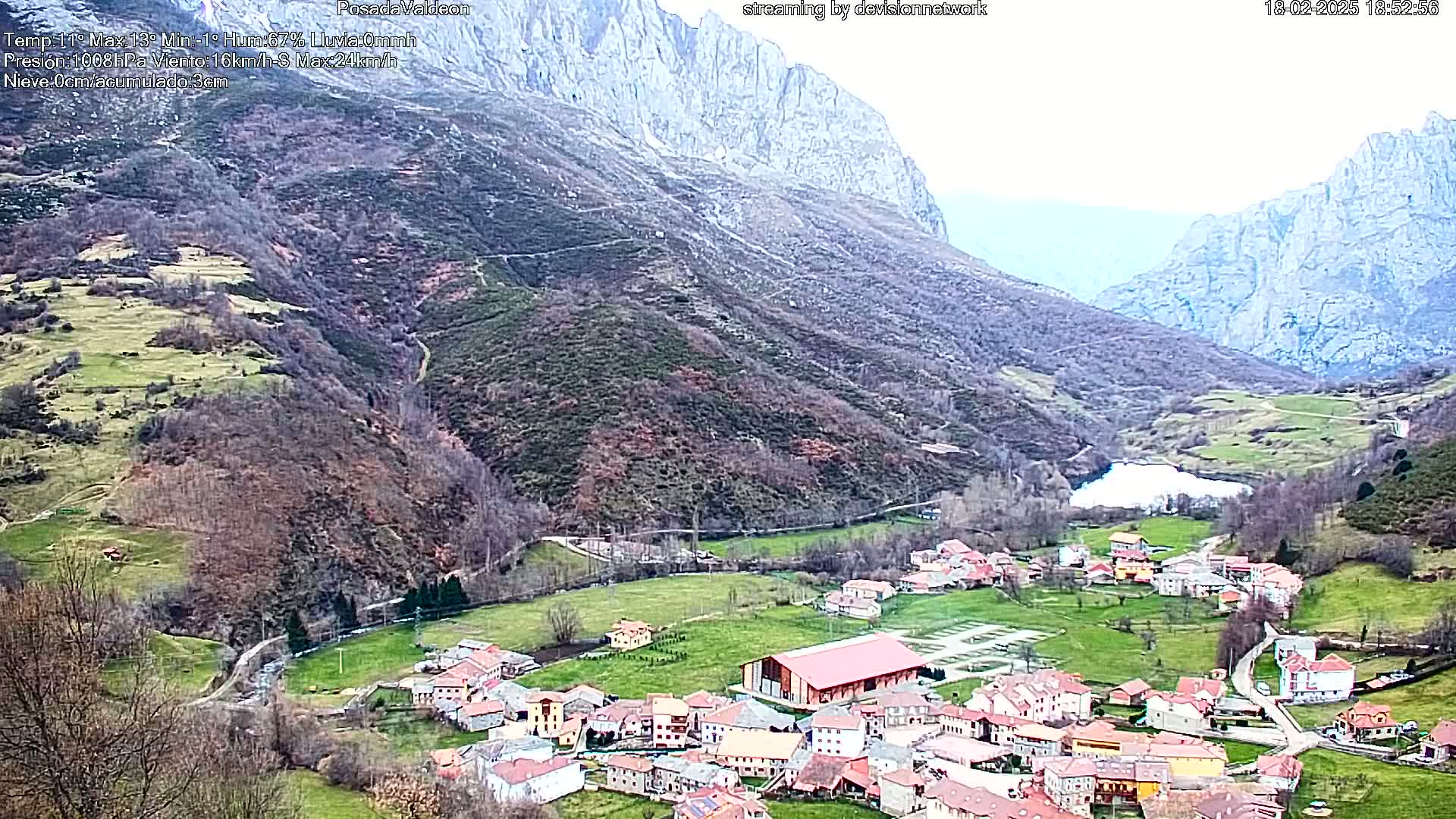 A small village nestled in a valley between steep, rocky mountains on an overcast day.