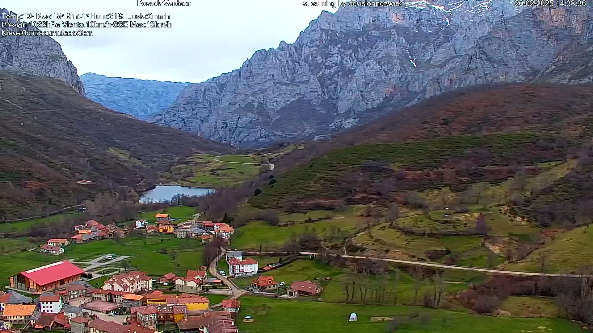 A small village nestled in a valley between large, rocky mountains under an overcast sky.