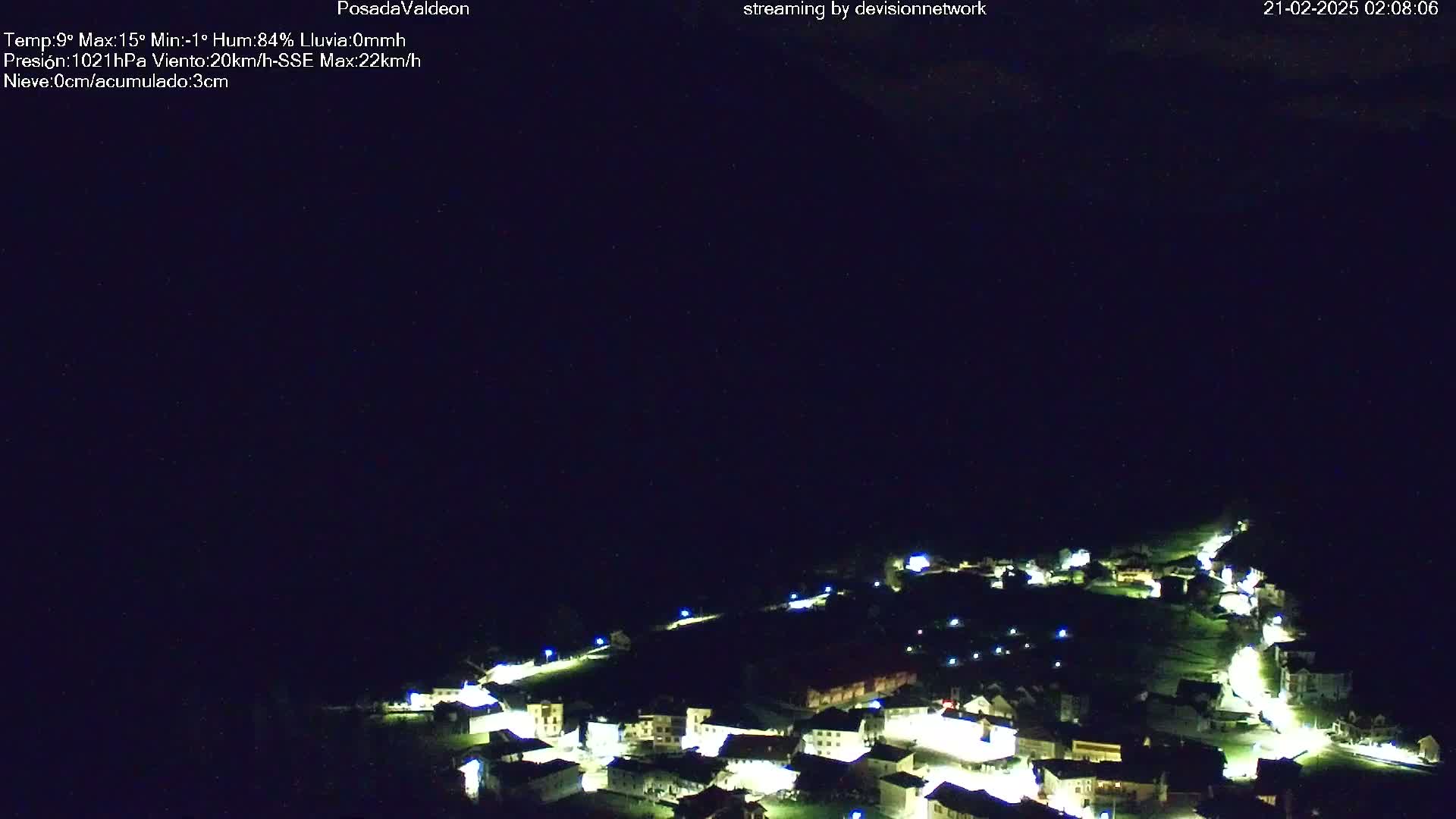 A nighttime aerial view of a small village illuminated with lights under a dark, clear sky.