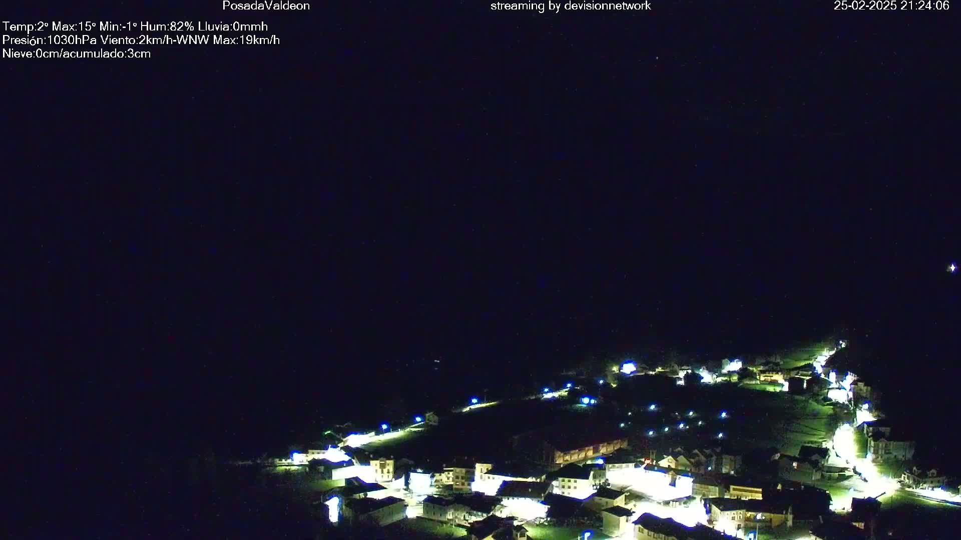 A small village at night is illuminated under a clear, dark sky.