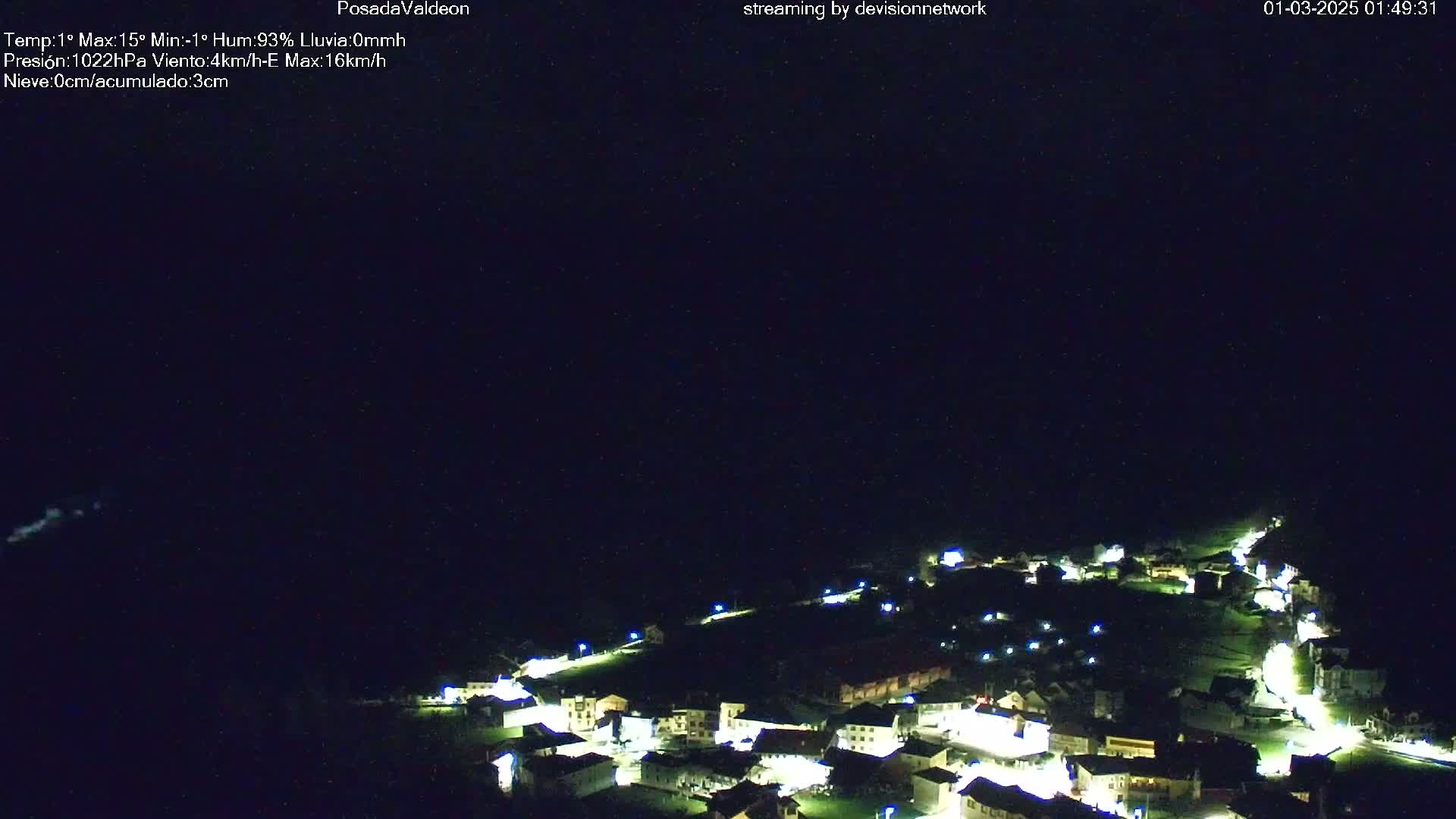 A nighttime aerial view of a small town illuminated by lights under a clear, dark sky.