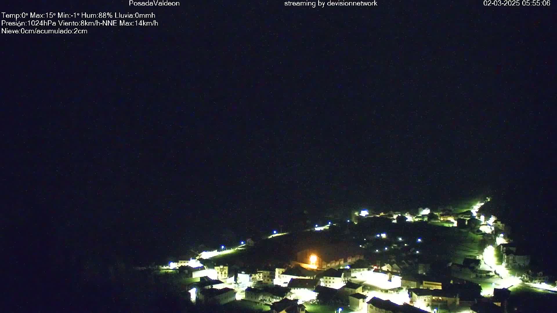 A nighttime, aerial view of a small, illuminated village under a clear, dark sky.