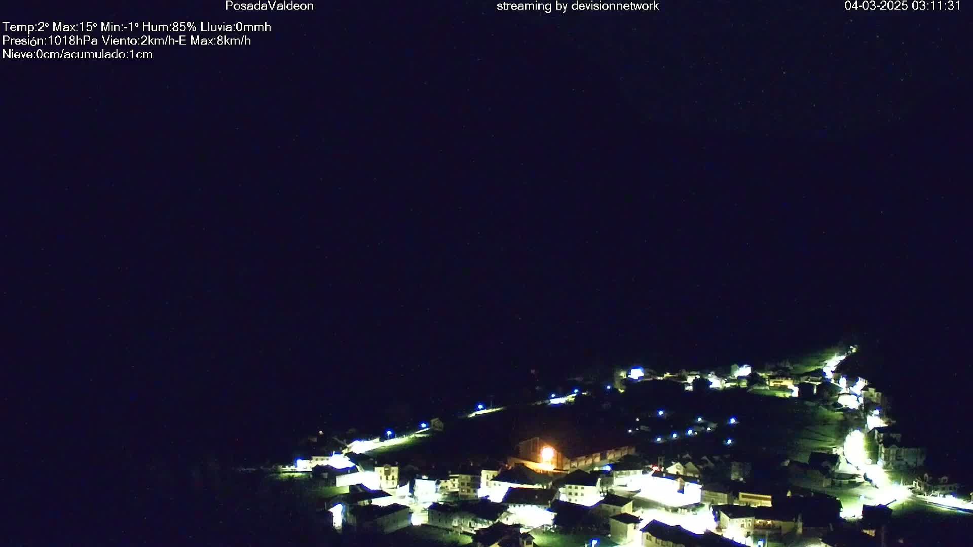 A nighttime aerial view of a small village illuminated by lights under a clear, dark sky.