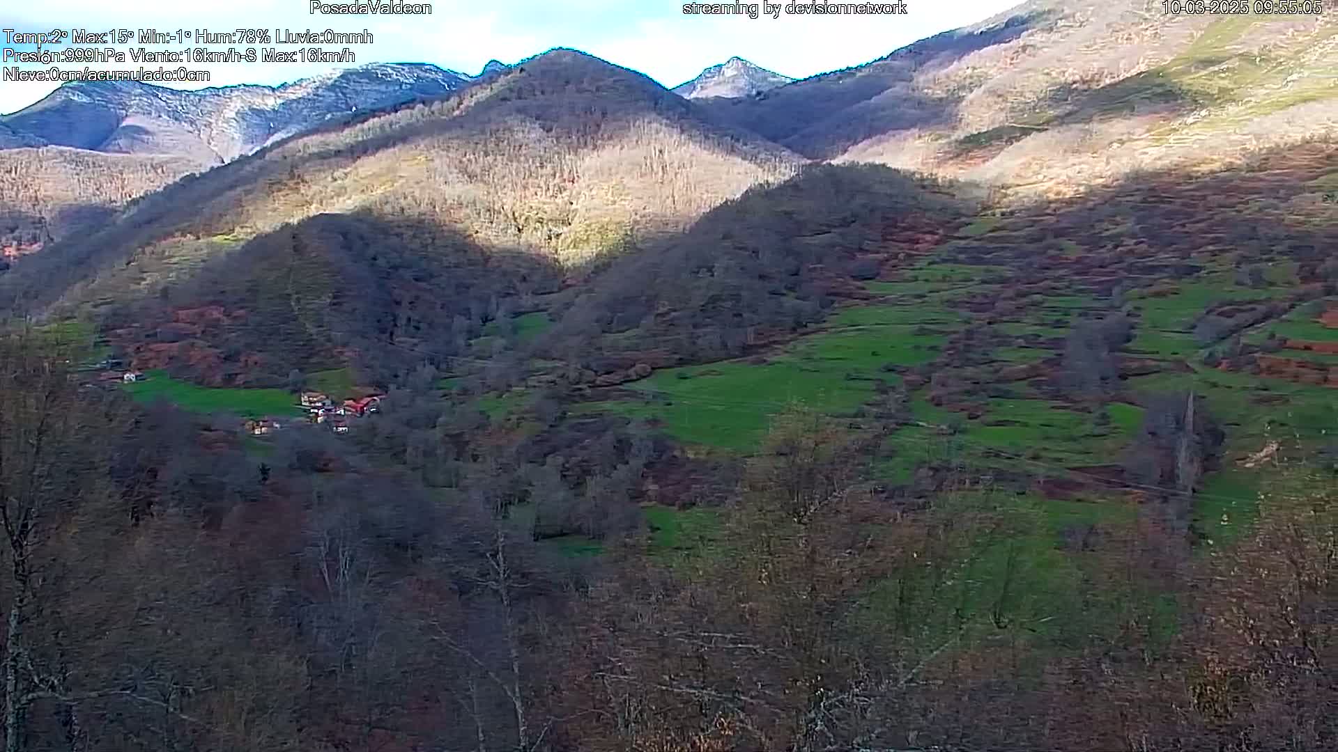 A sunny day reveals a valley nestled between brown and green hillsides, with a small village visible in the lower section.