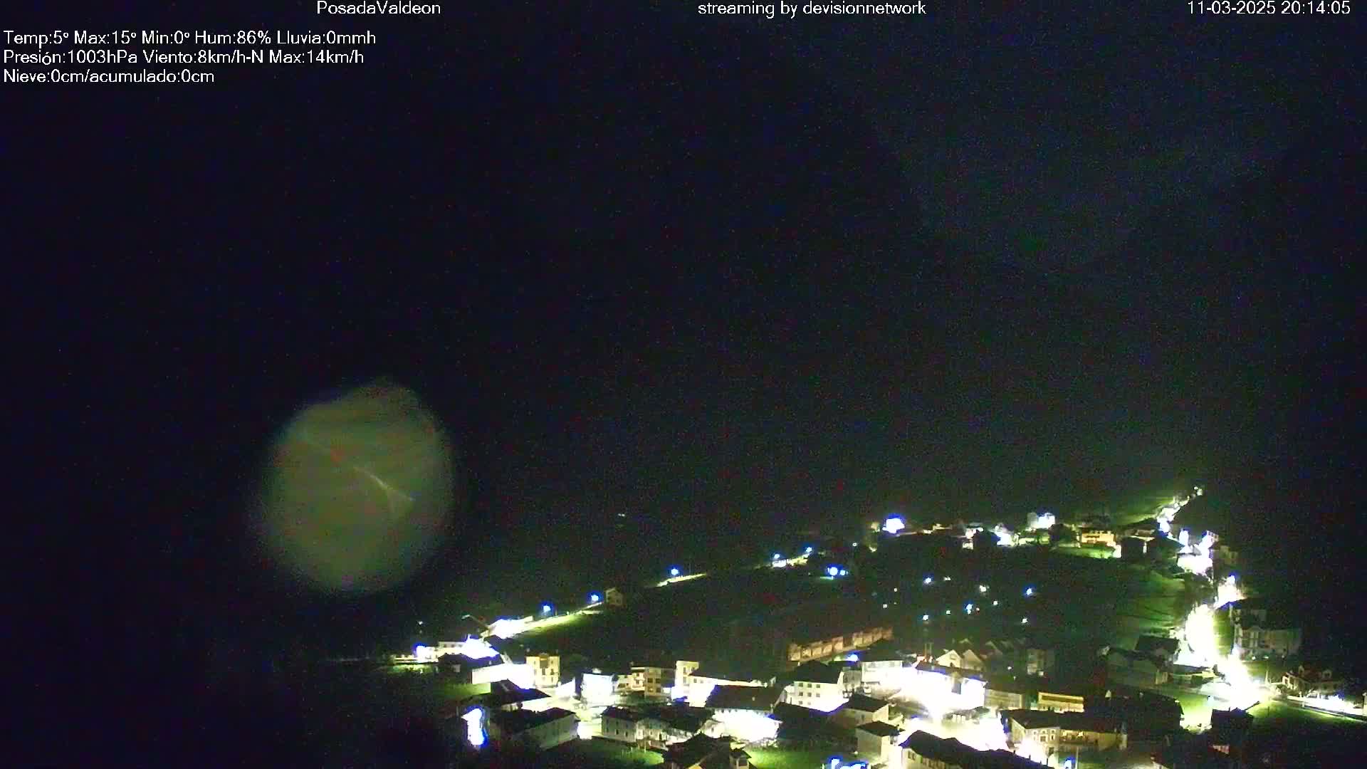 A nighttime, aerial view of a small, illuminated town under a dark, cloudy sky.