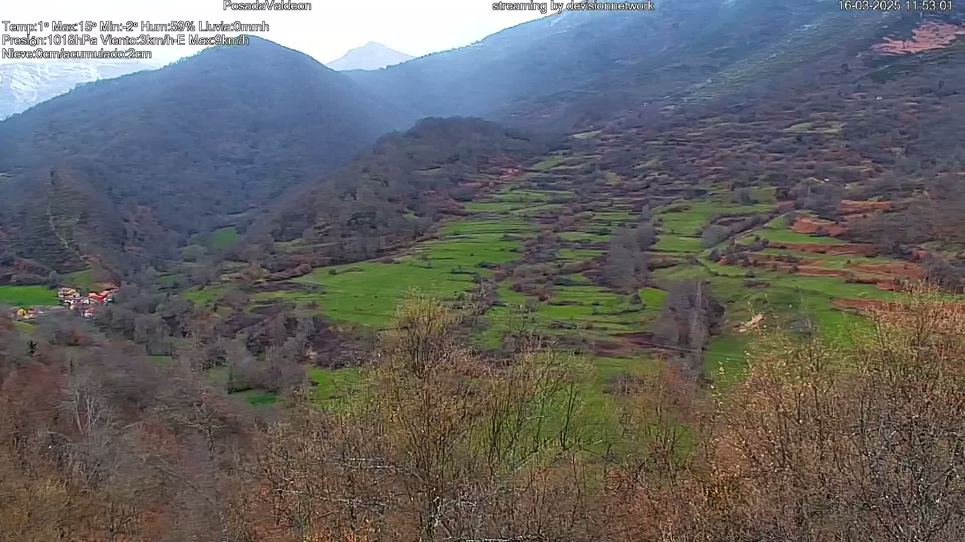 A mountainous valley with terraced fields of green and brown, under an overcast sky.