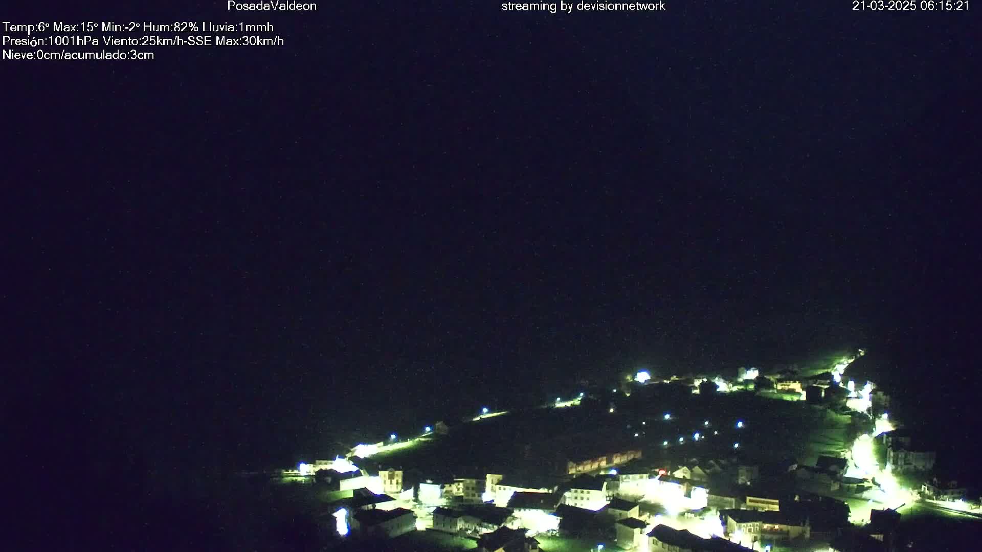 A nighttime aerial view of a small, illuminated town under a dark, slightly hazy sky.