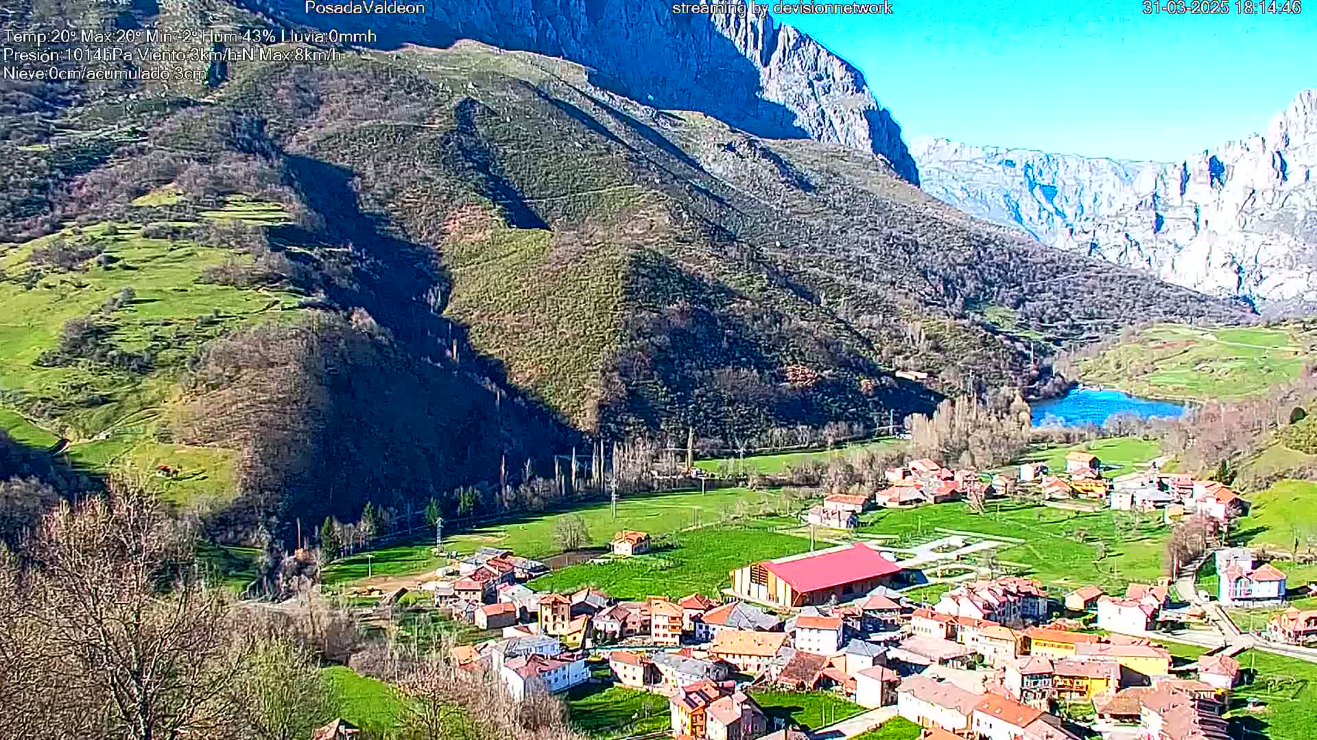 A small village nestled in a valley between steep, rocky mountains on a sunny day.