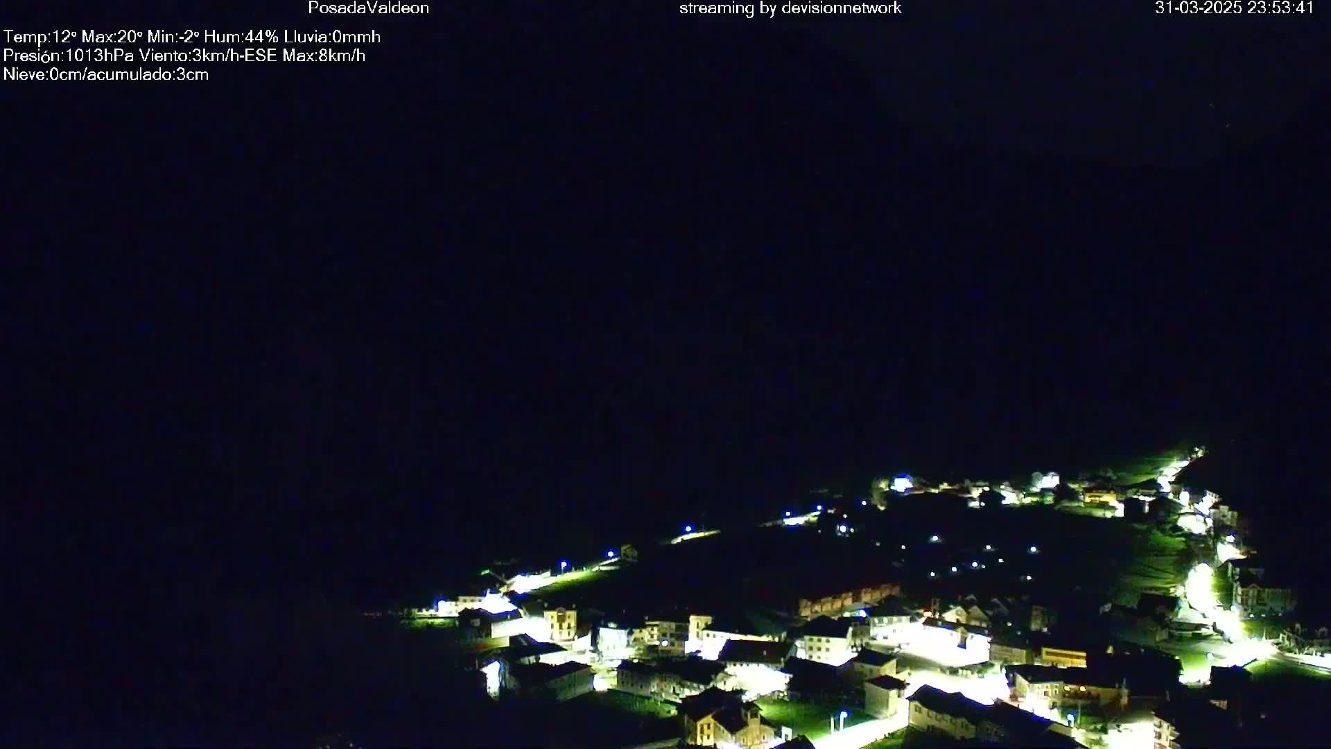 A nighttime, high-angle view of a small village illuminated by streetlights under a dark, clear sky.