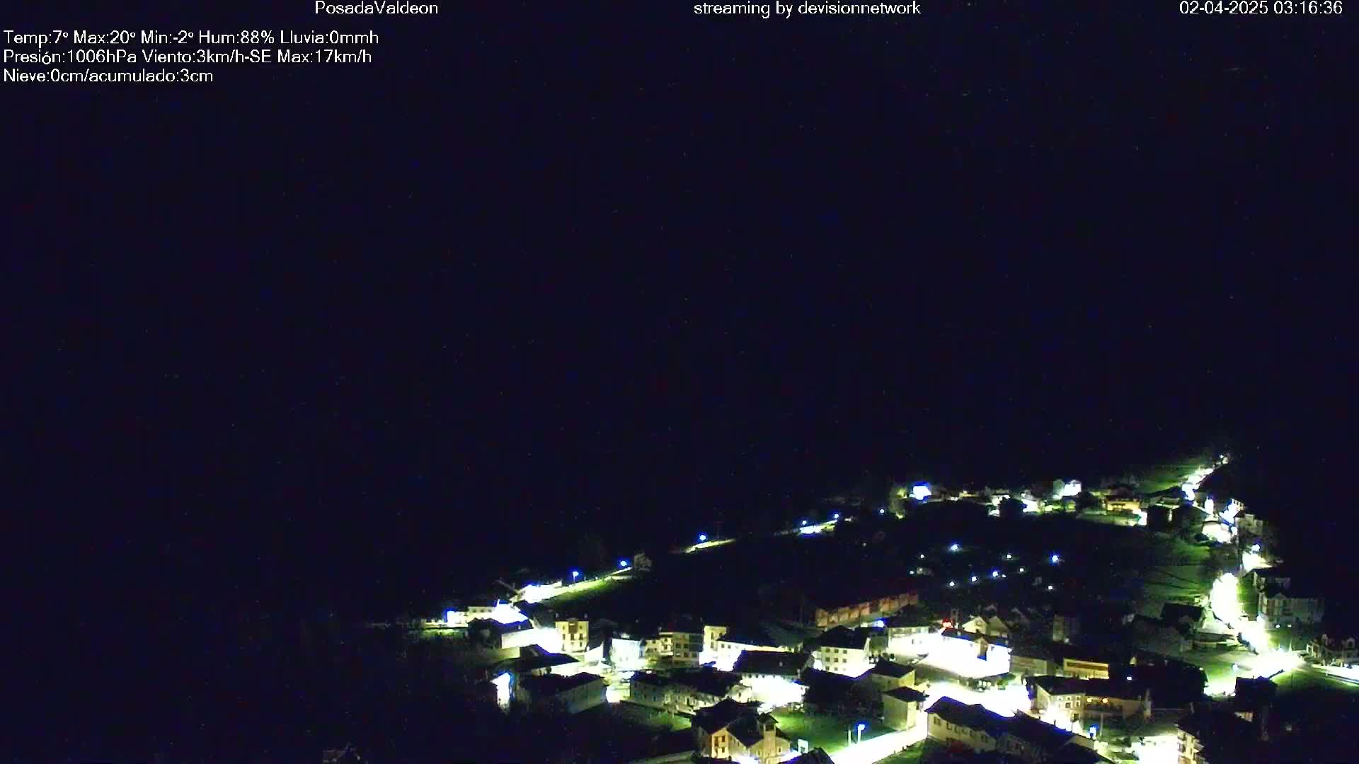 A small, illuminated village is nestled in a dark, nighttime landscape.