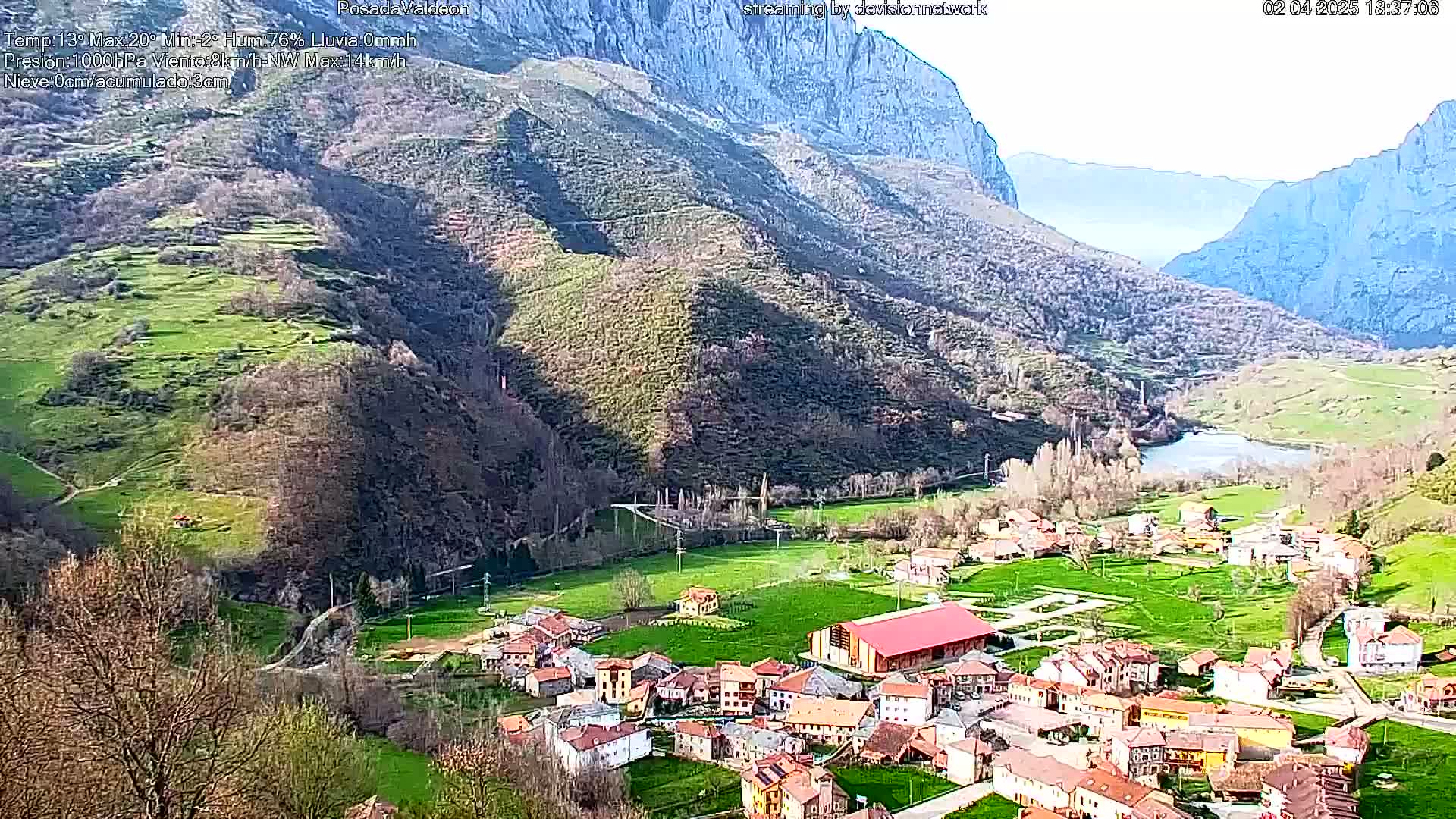 A small village nestled in a valley between mountains on a partly sunny day.