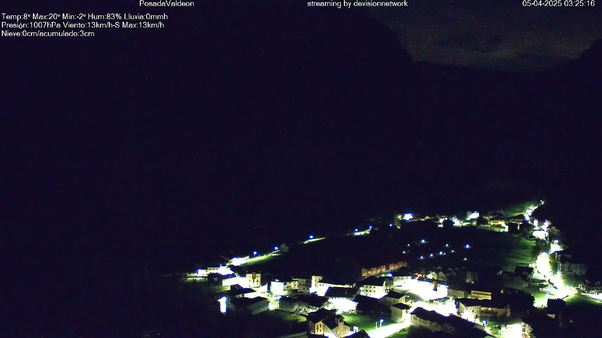 A nighttime, aerial view of a small village nestled in a valley under a dark sky.