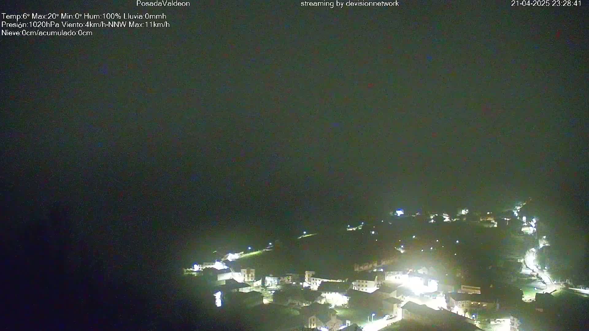 A nighttime, aerial view of a small town illuminated by lights under a dark, overcast sky.